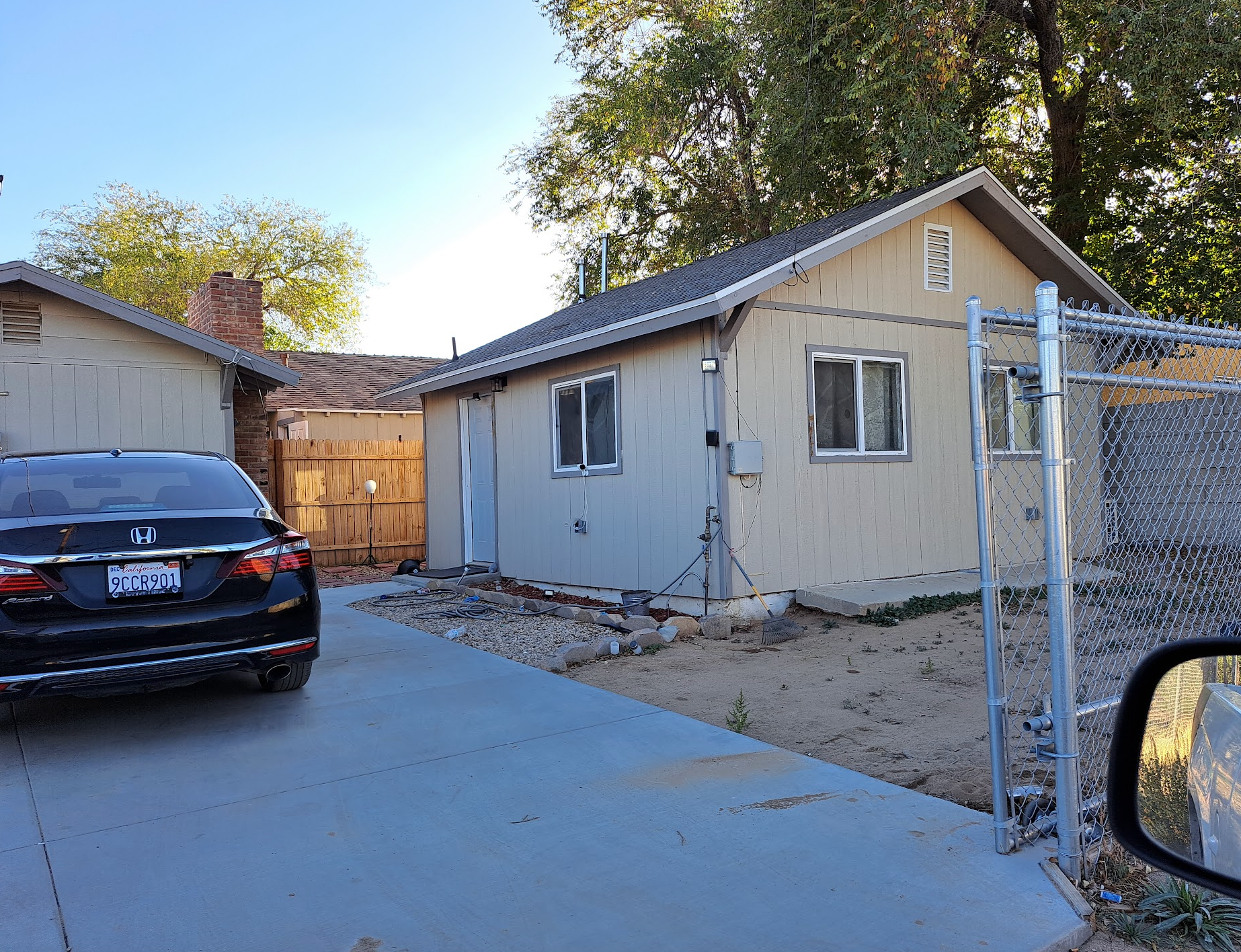 A black car is parked in front of a small house