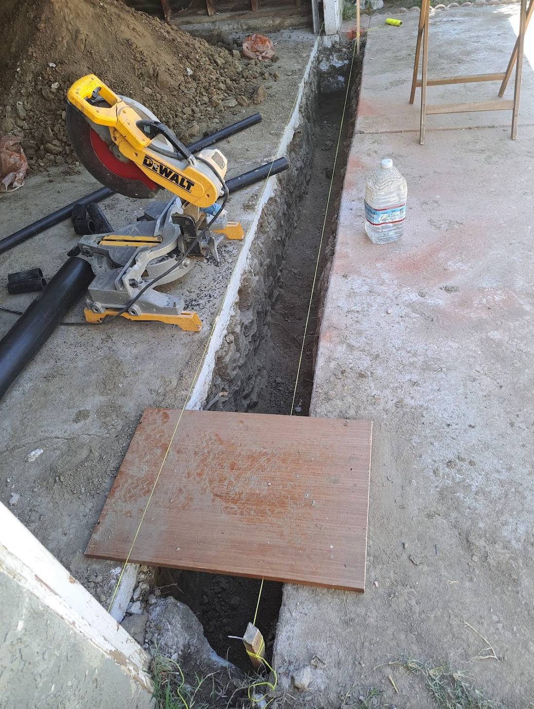 A circular saw is sitting on the ground next to a piece of wood.