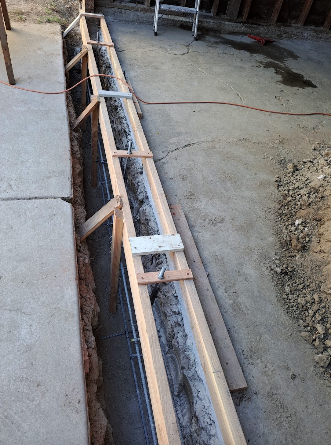 A concrete wall is being built with a ladder in the background.