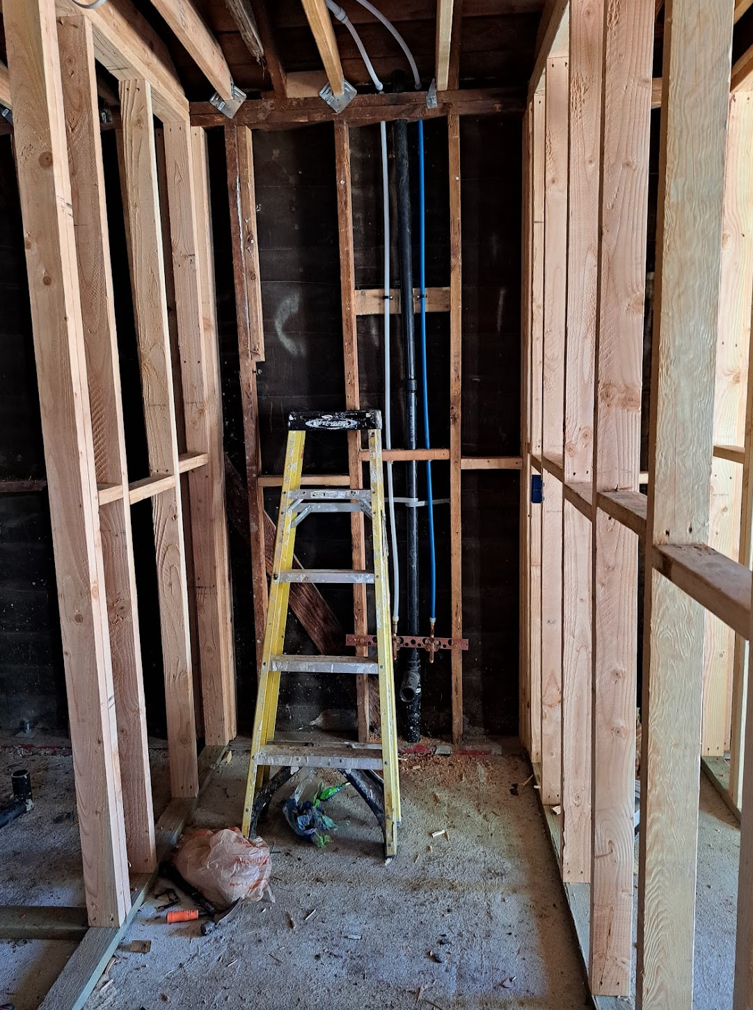 A ladder is sitting in the middle of a room under construction.