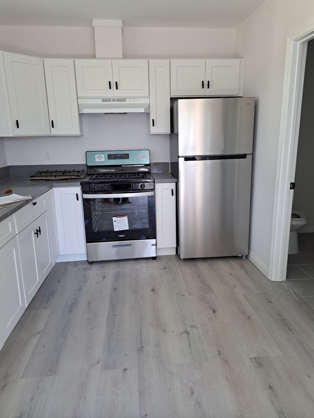 A kitchen with stainless steel appliances and white cabinets.