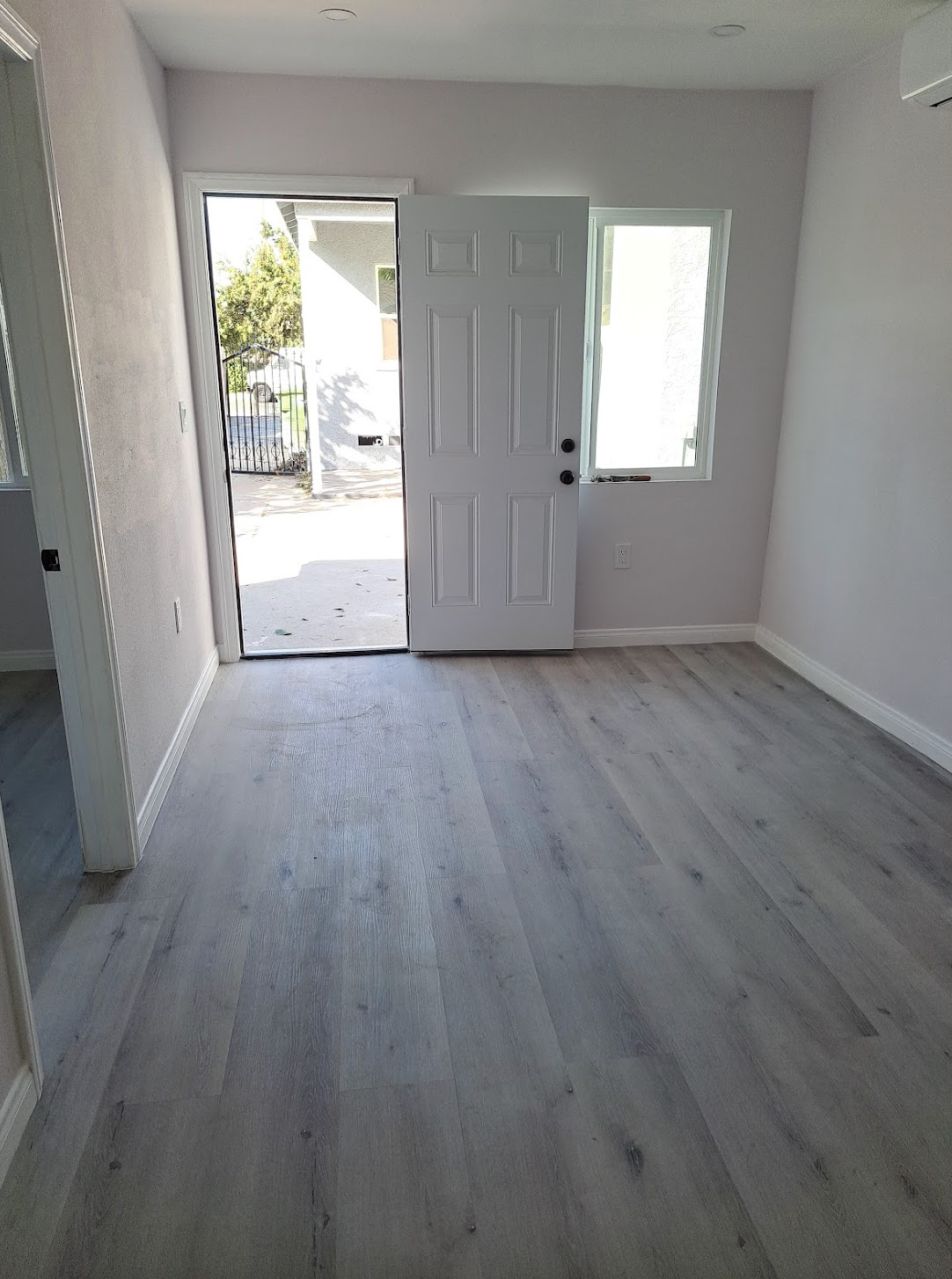 A living room with hardwood floors and a door that is open.