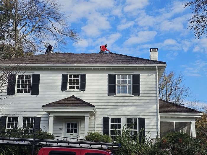 A man is working on the roof of a white house.