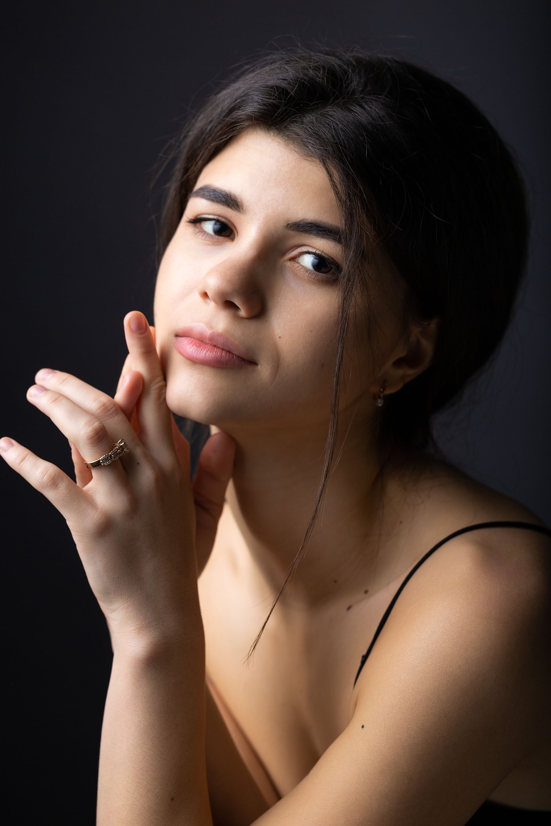 The woman is wearing a ring on her finger and has her hands on her face.