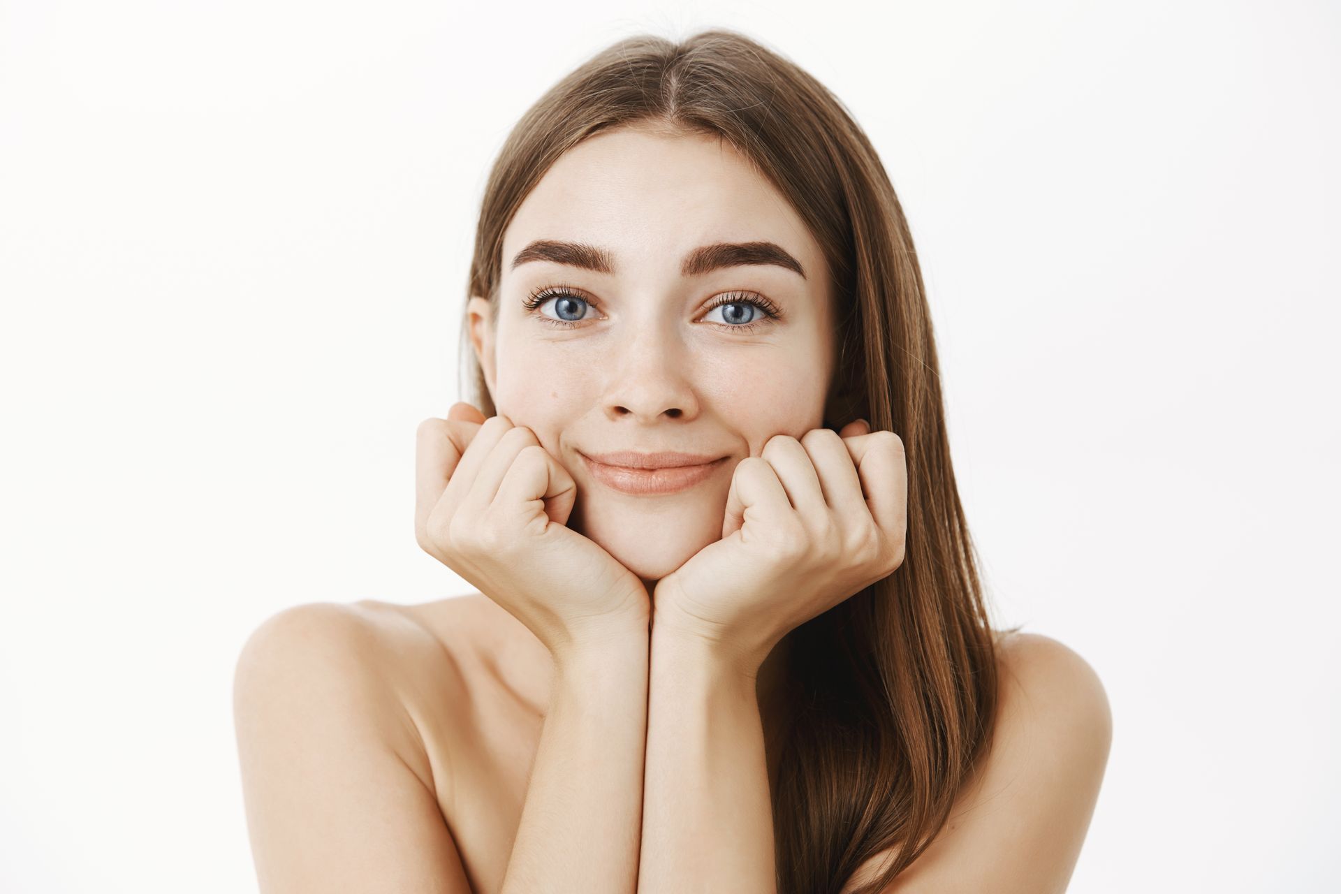 A woman is smiling with her hands on her face.