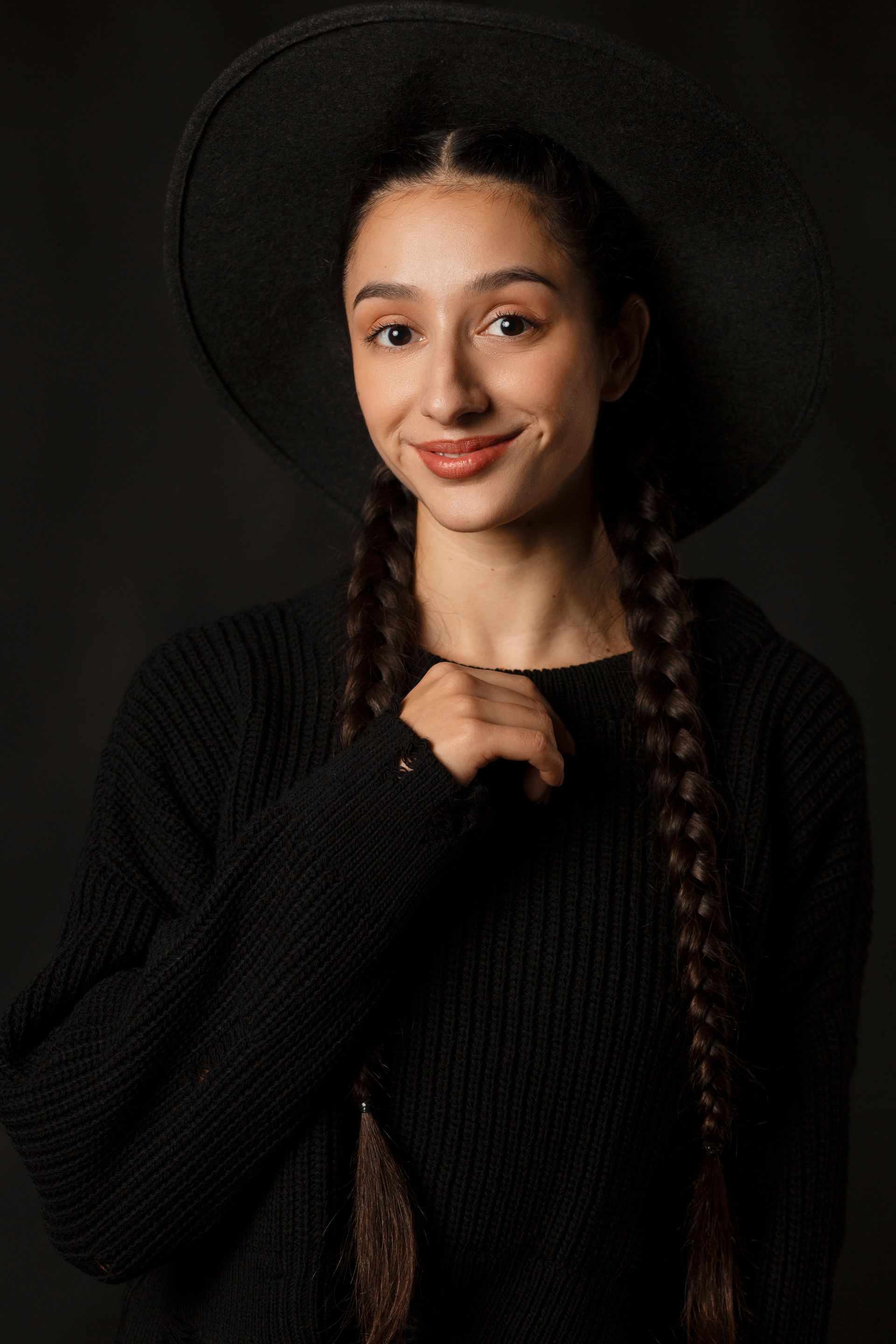 The woman is wearing a black hat and a black sweater.