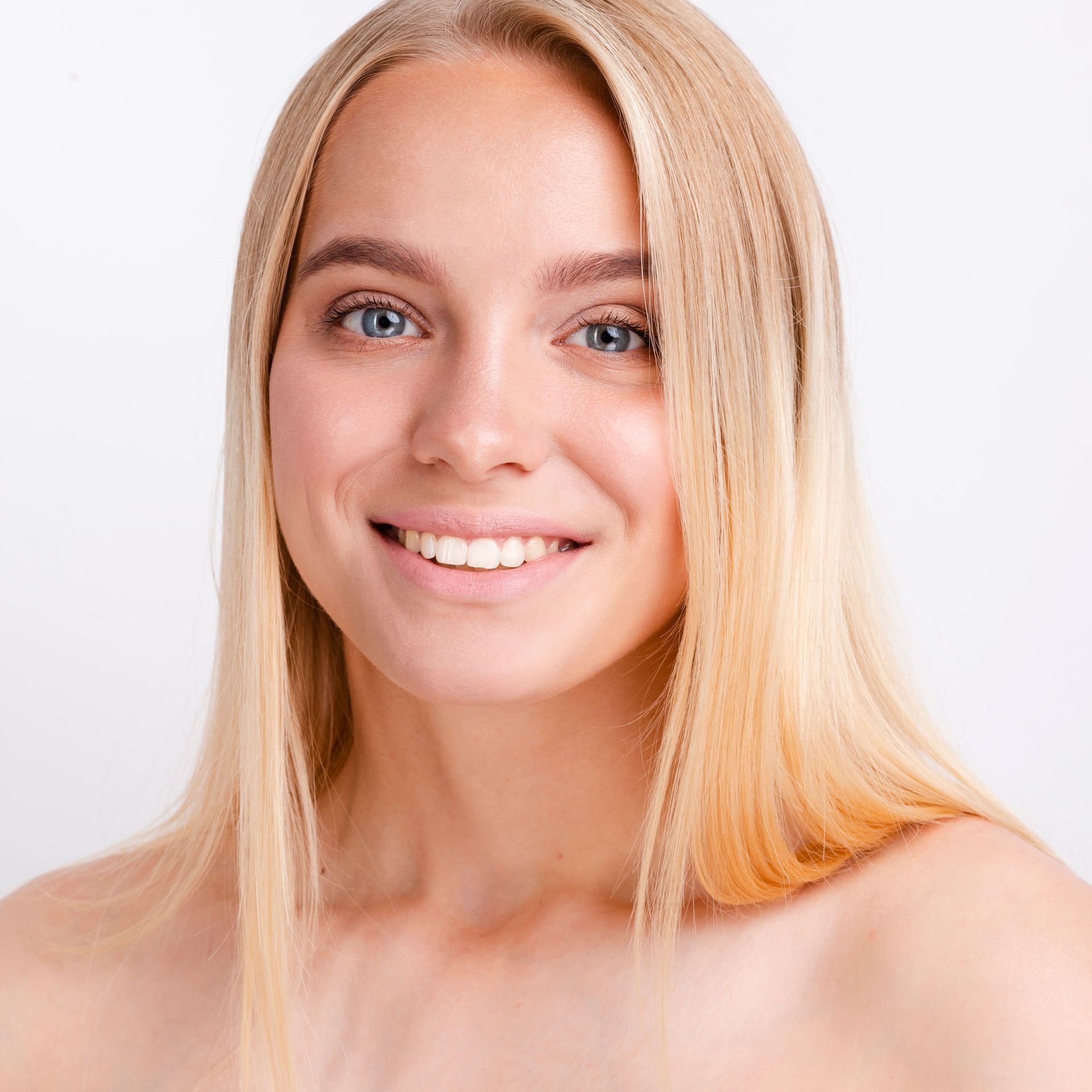 A woman with blonde hair and blue eyes is smiling for the camera.