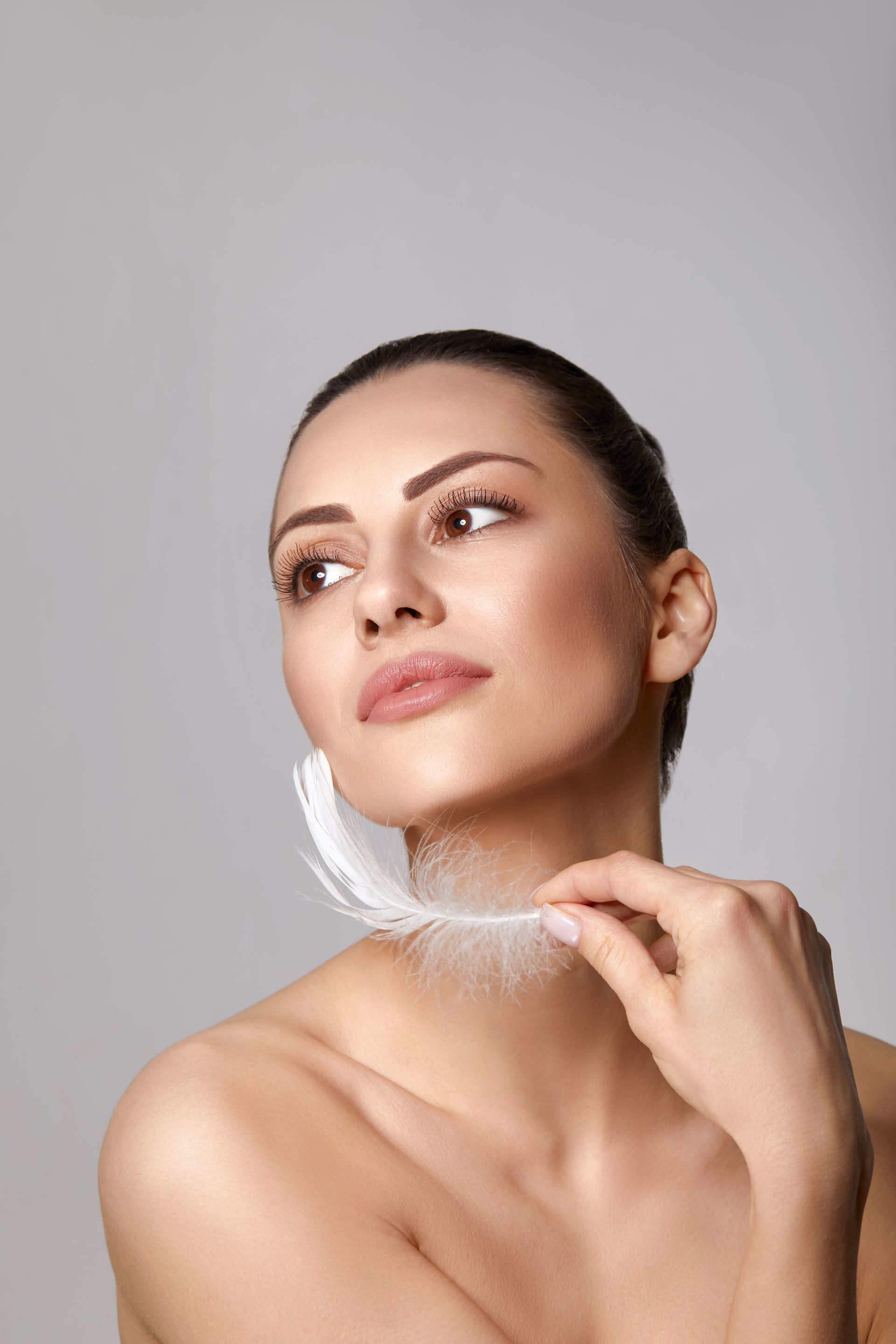 A woman is holding a white feather around her neck.