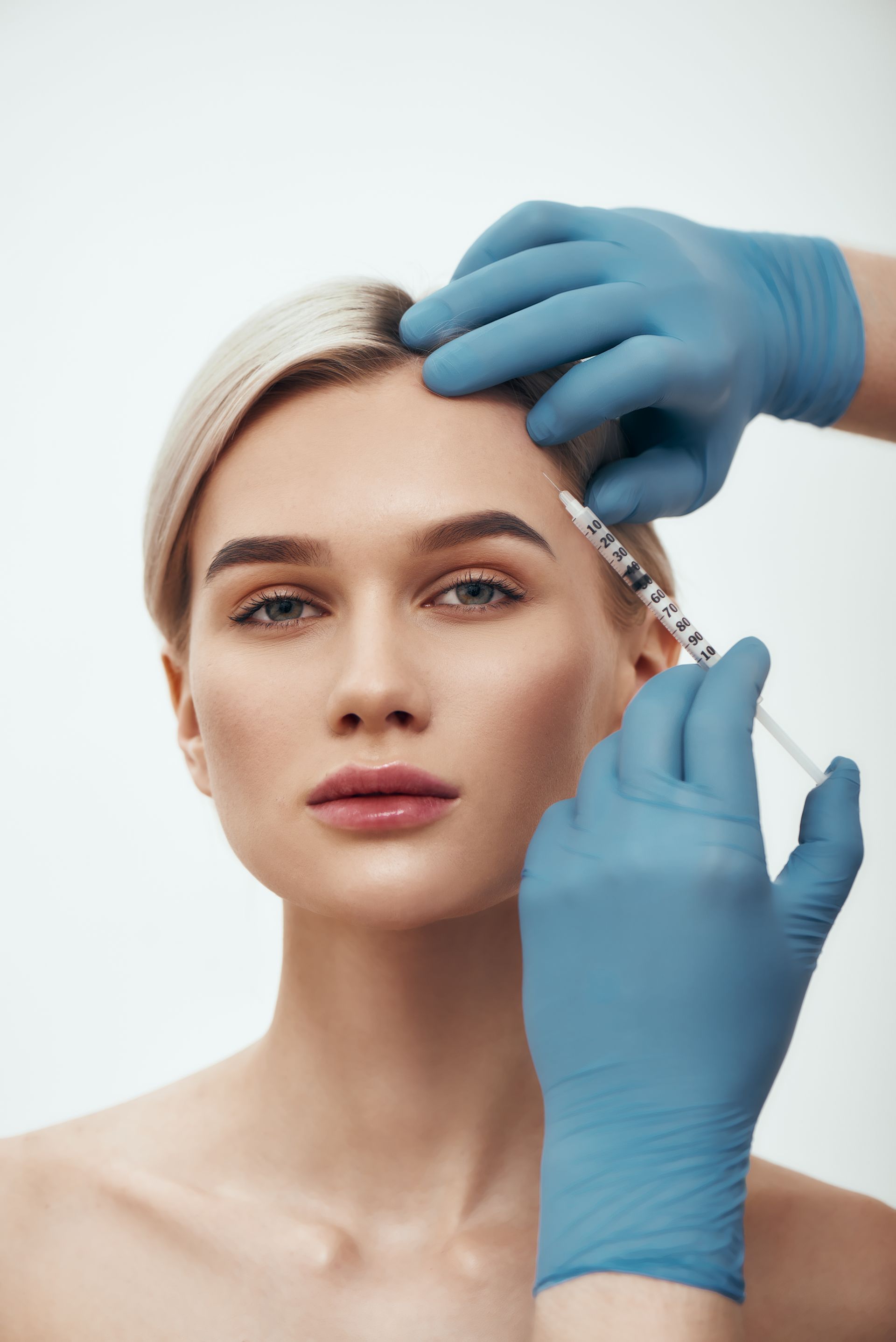 A woman is getting a botox injection in her forehead.