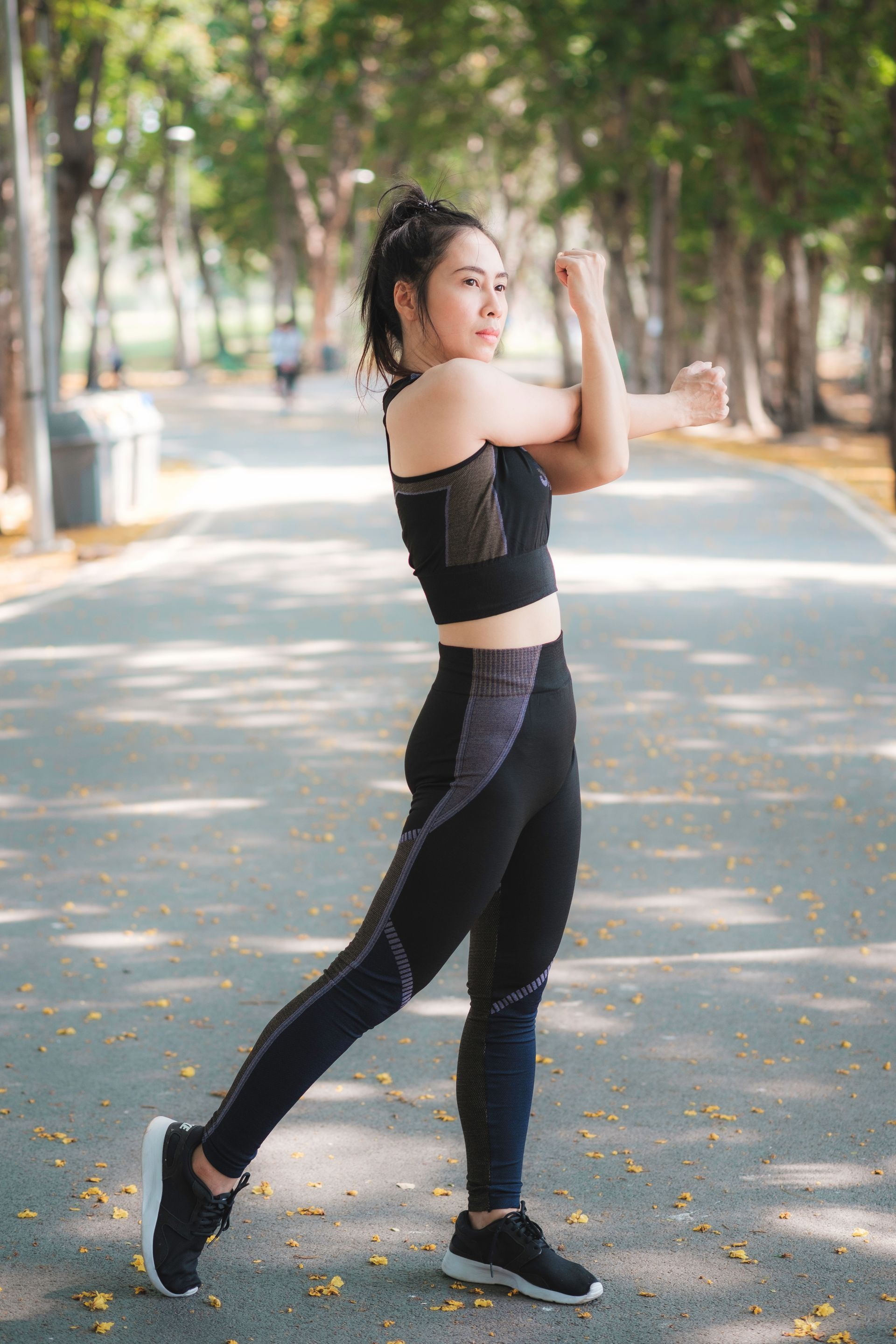 A woman is standing on a road with her arms outstretched.