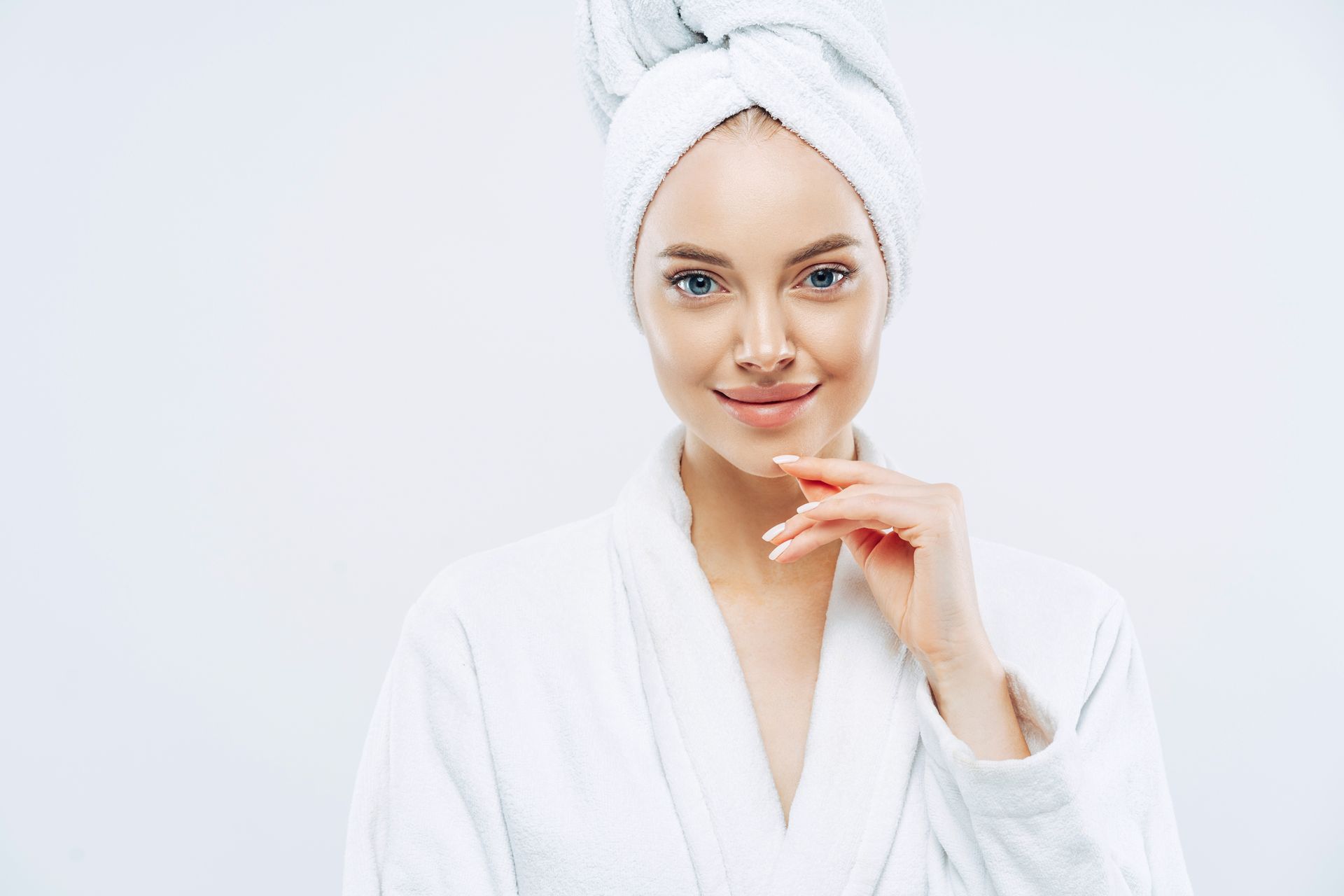 A woman in a bathrobe with a towel wrapped around her head.