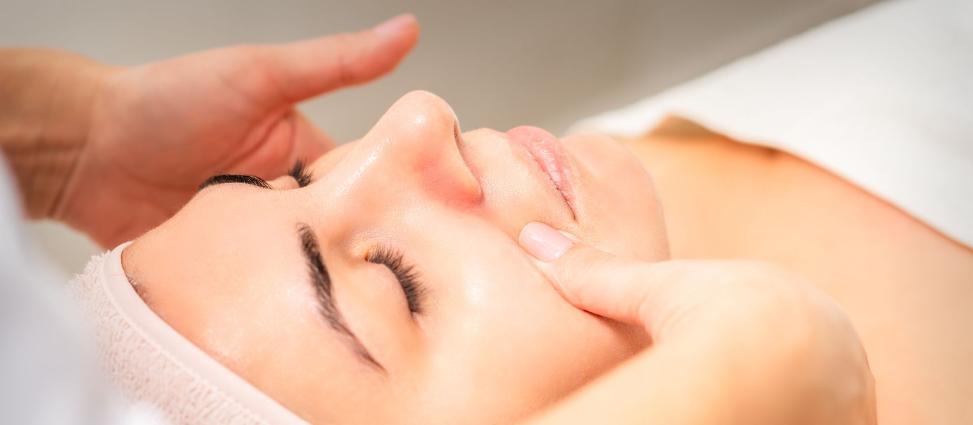 A woman is getting a facial massage at a spa.