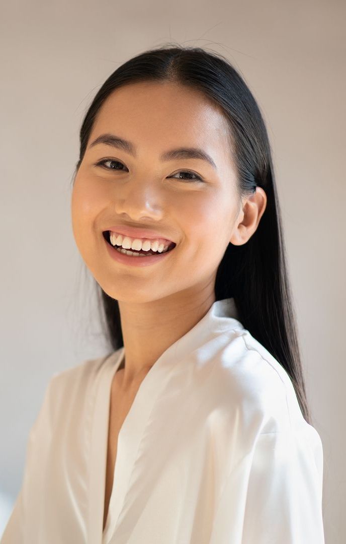 A woman in a white robe is smiling for the camera.