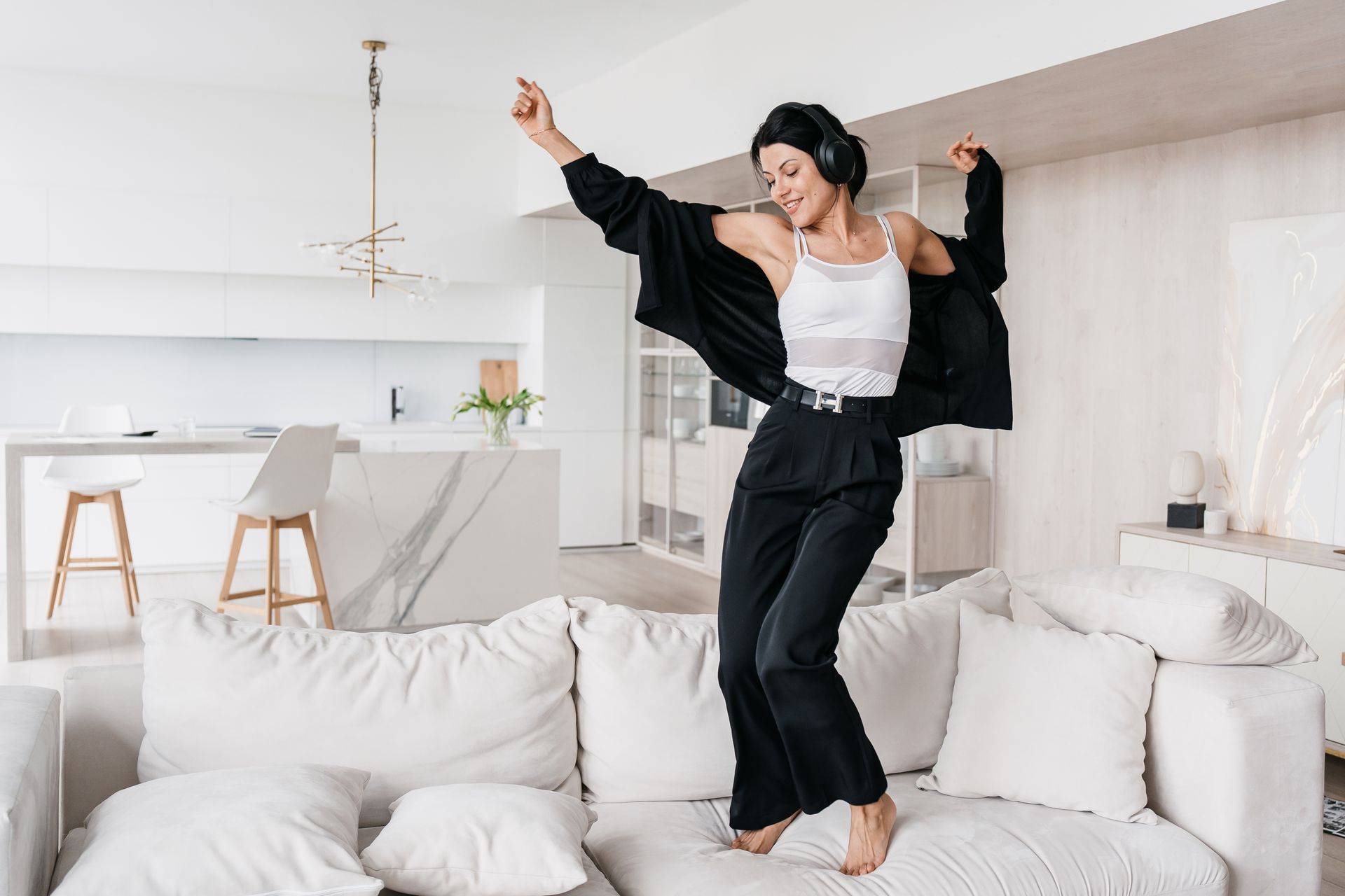 A woman is jumping on a couch in a living room.