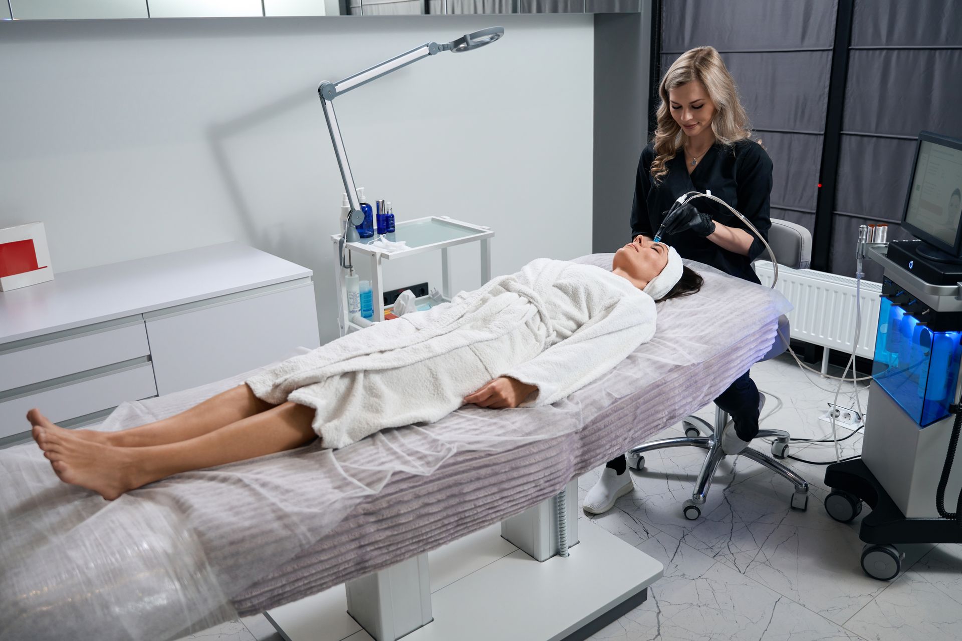 A woman is laying on a bed getting a facial treatment.