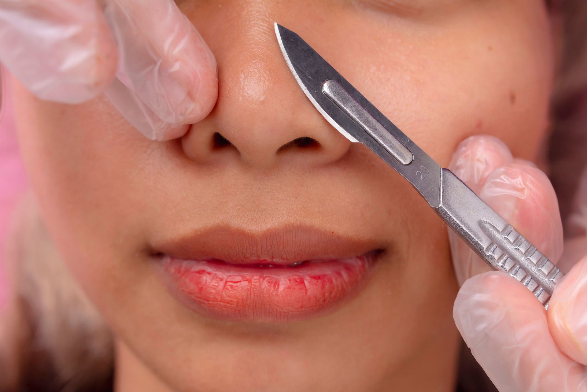 A woman is getting her nose waxed with a scalpel.