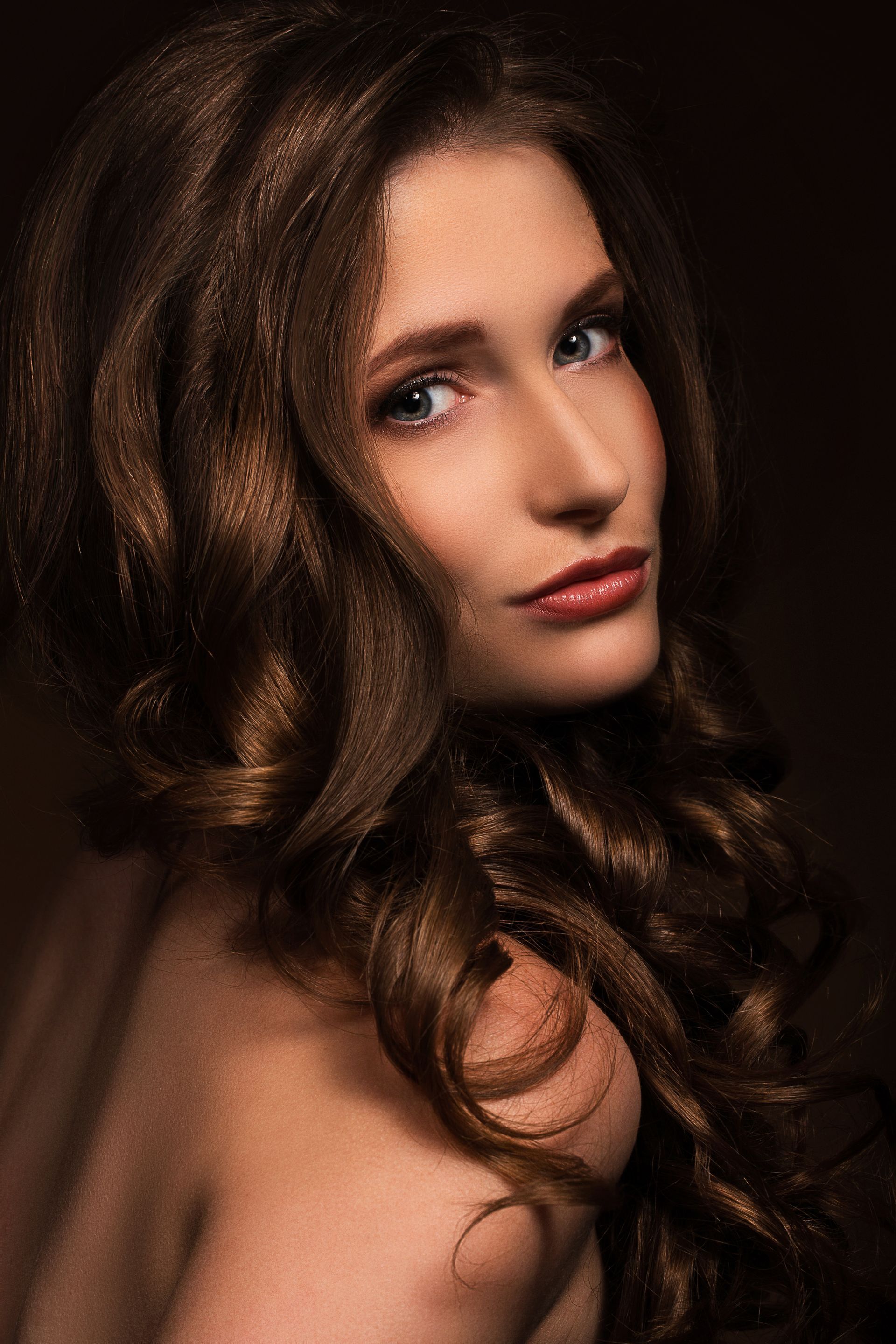 A woman with long brown hair is looking at the camera.