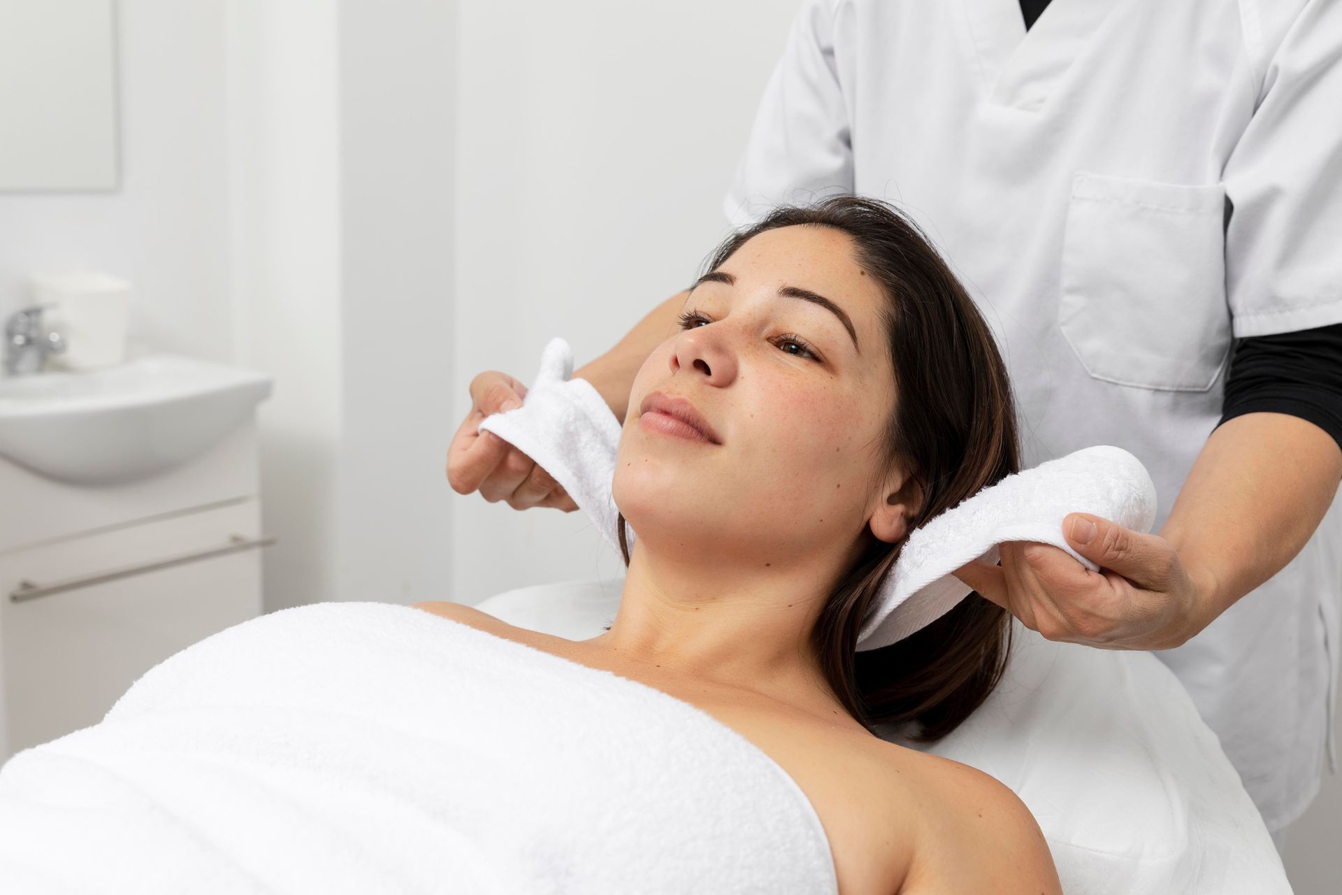 Young woman receiving a spa or beauty treatment at a salon, lying down with a towel.