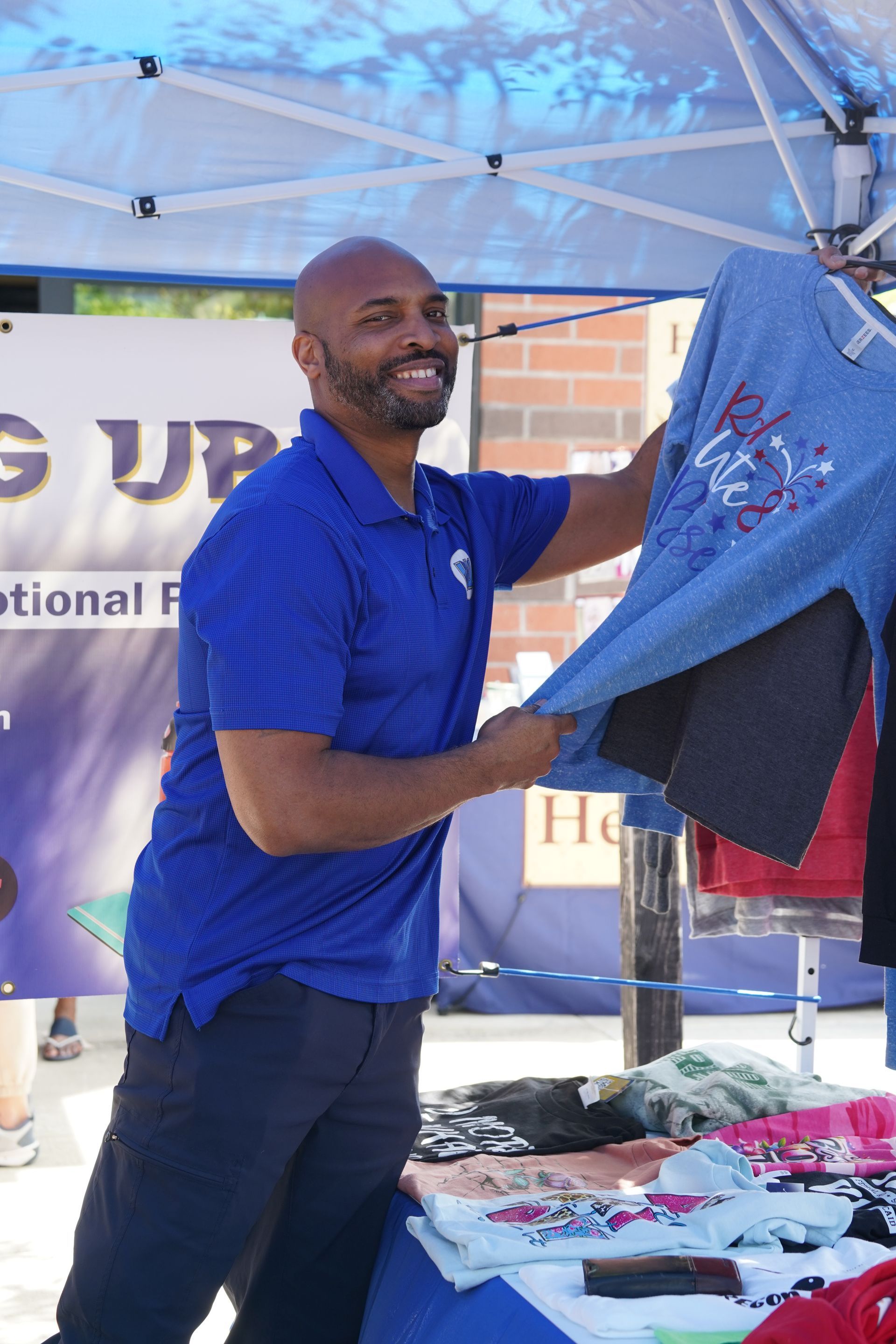A man in a blue shirt is holding a denim shirt