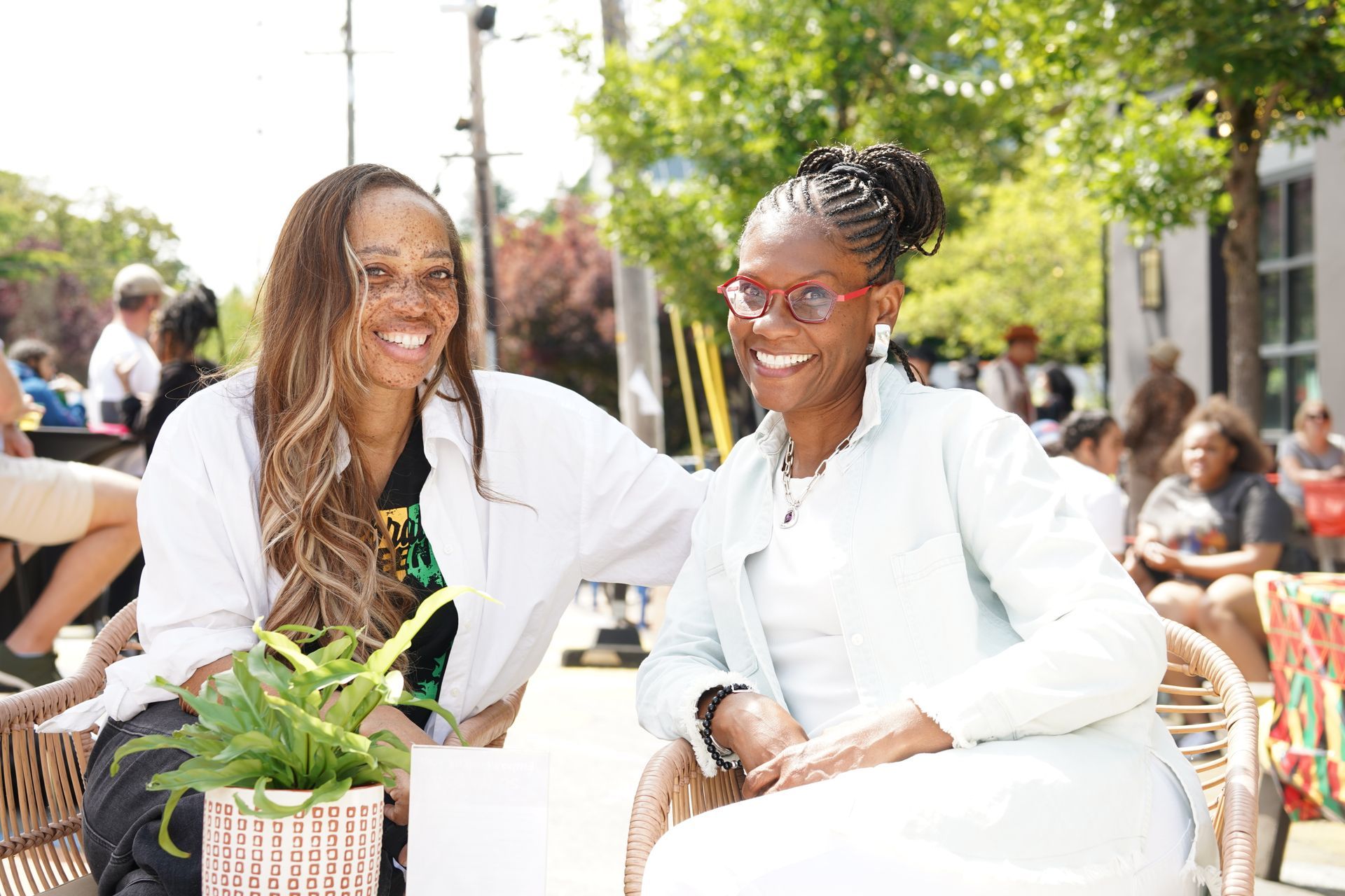 Two women are sitting next to each other on a bench and smiling.