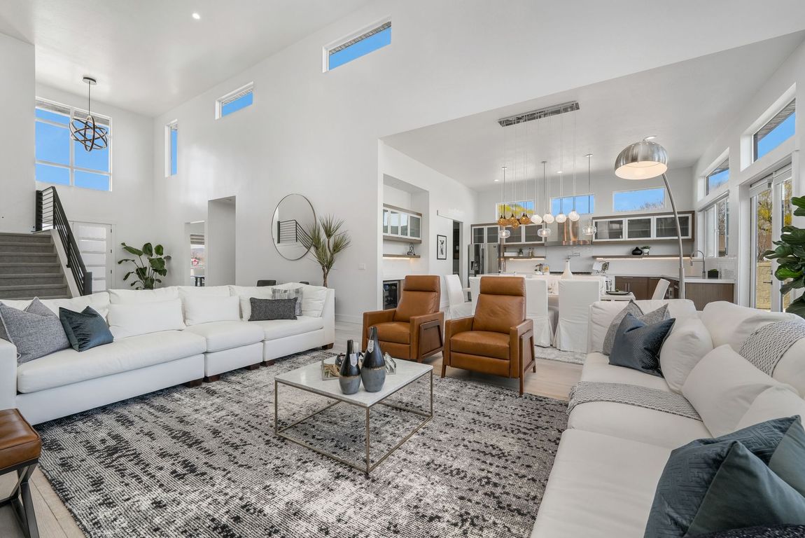 A kitchen with white cabinets , stainless steel appliances , hardwood floors and a large island.