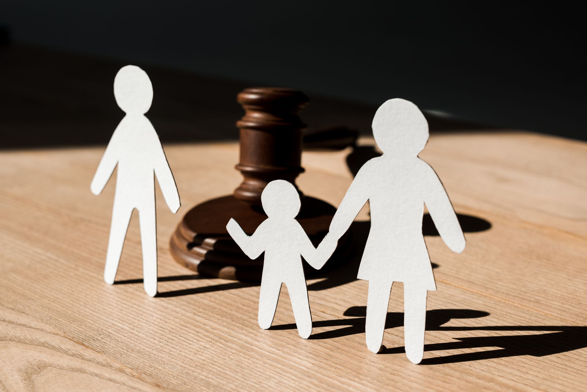 Paper cutouts of a family in front of a wooden gavel.