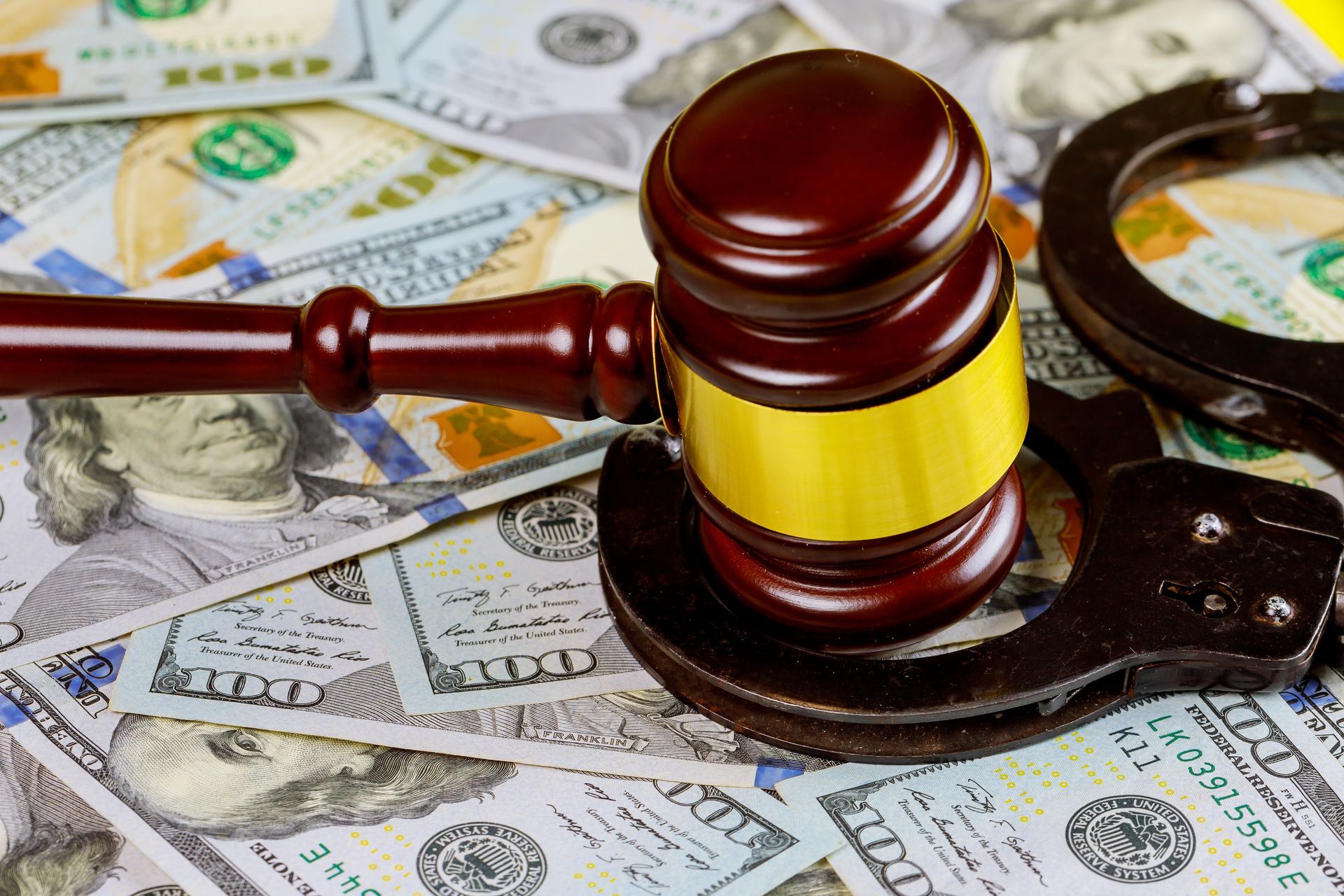 Gavel and handcuffs on a bed of US dollar bills.