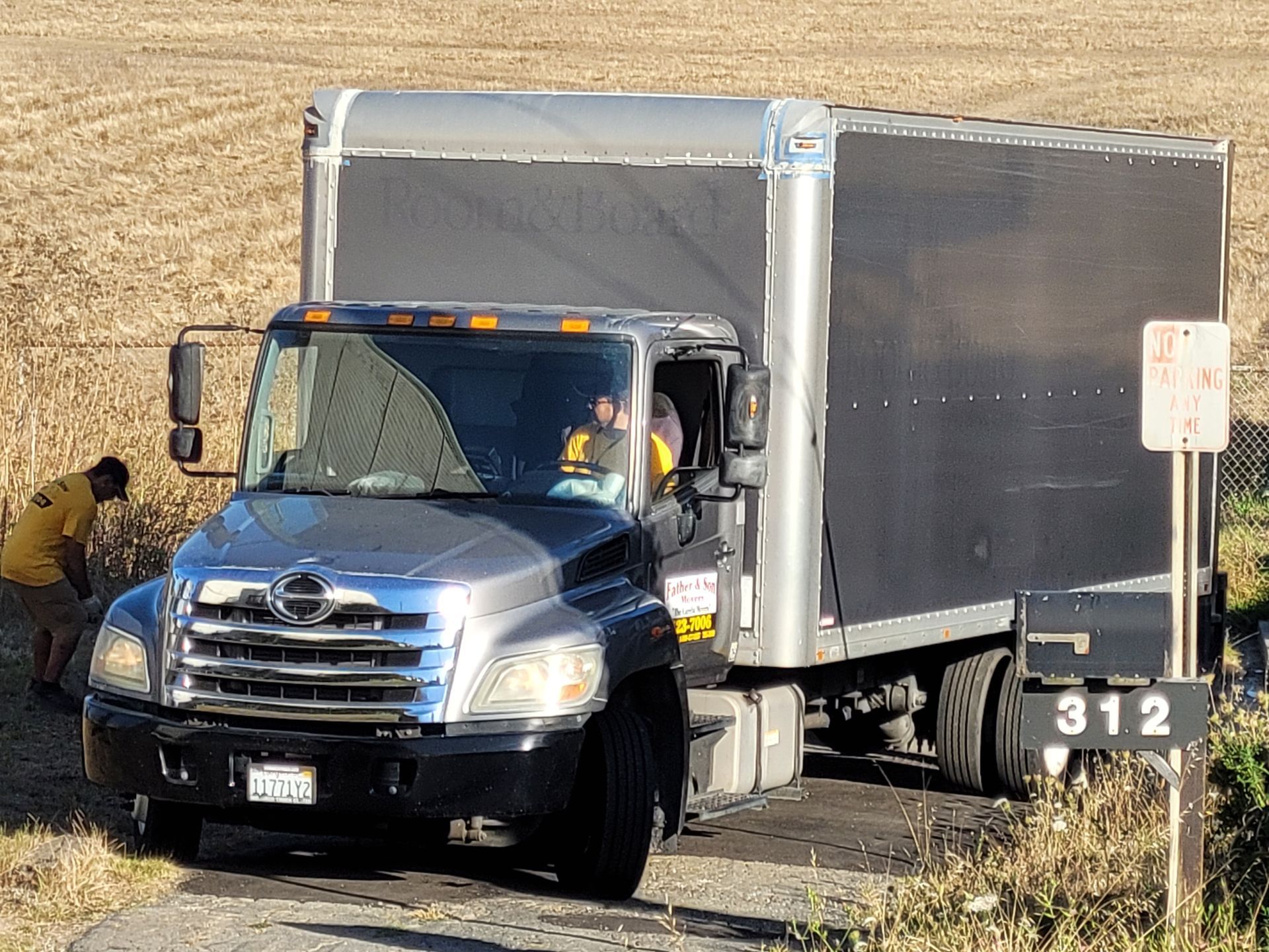 A truck is driving down a dirt road next to a field.