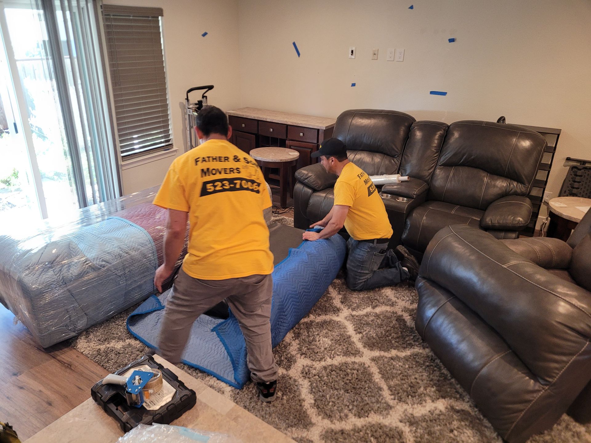 Two men are moving furniture in a living room.