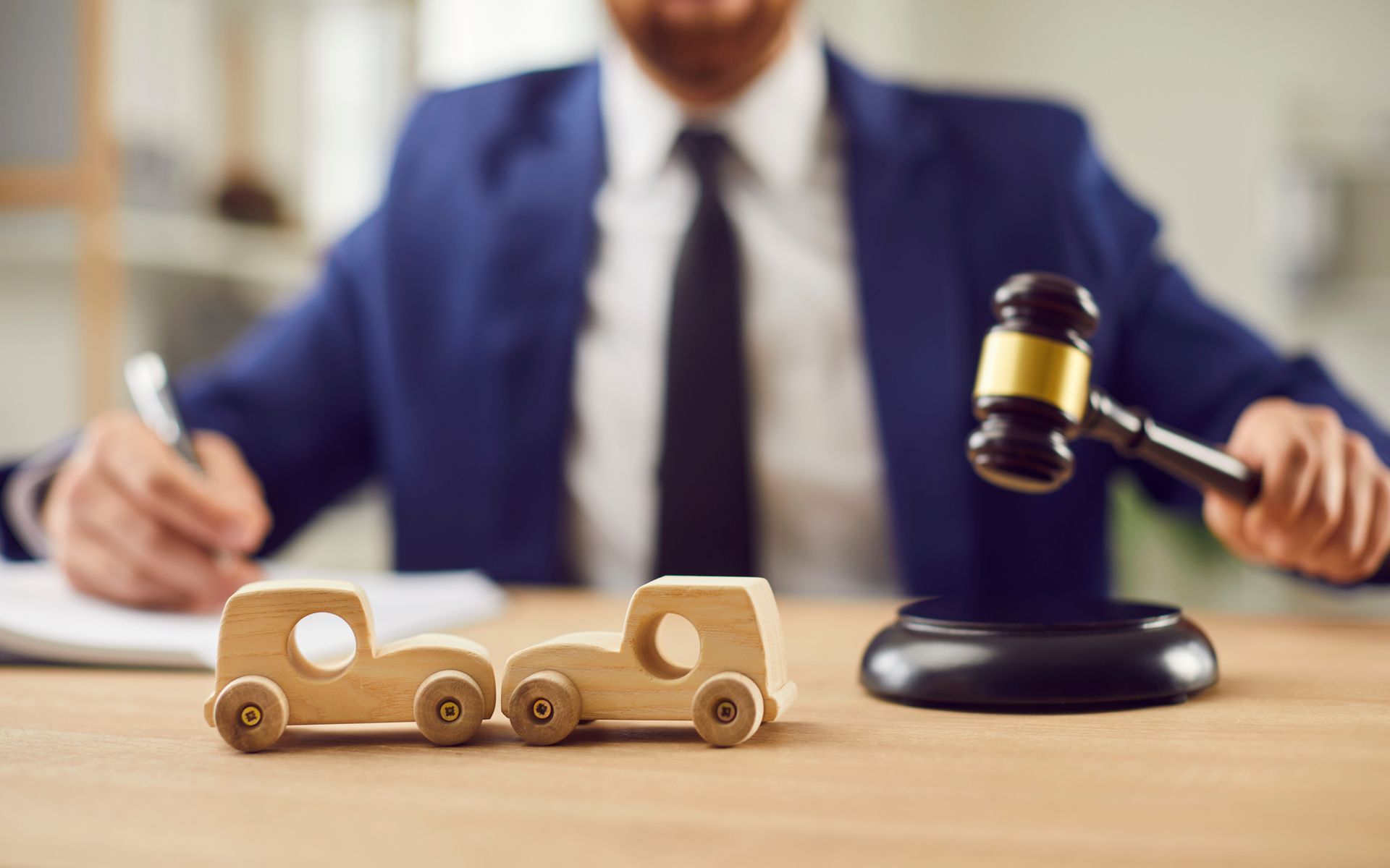 A man in a suit and tie is holding a judge 's gavel next to a wooden toy truck.