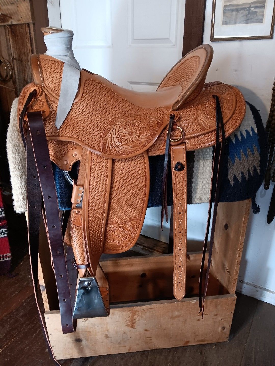 Brown leather western saddle on a wooden stand in a room