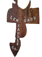 Wooden sign shaped like a fish, painted with &ldquo;LEN BABB SADDLE CO.&rdquo;