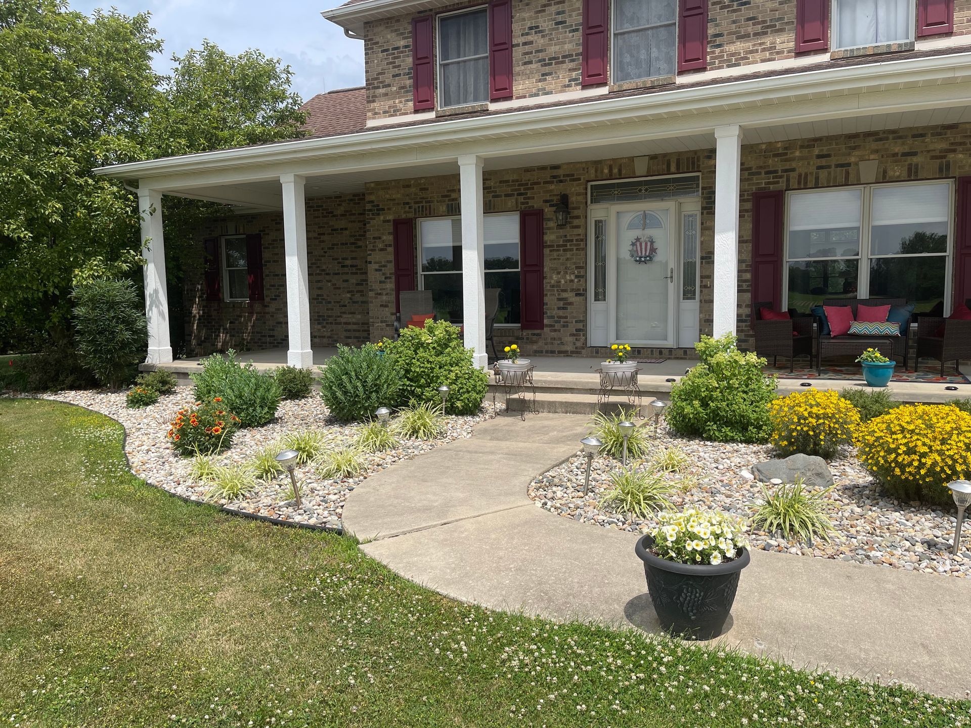 A large brick house with a porch and flowers in front of it.