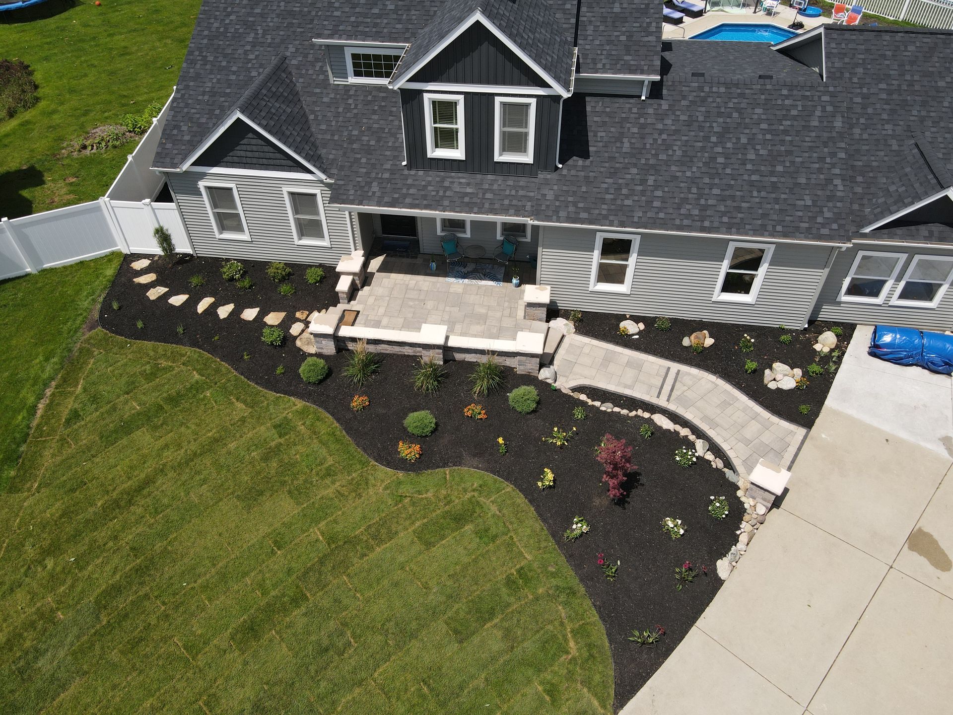 An aerial view of a large house with a swimming pool in the background.