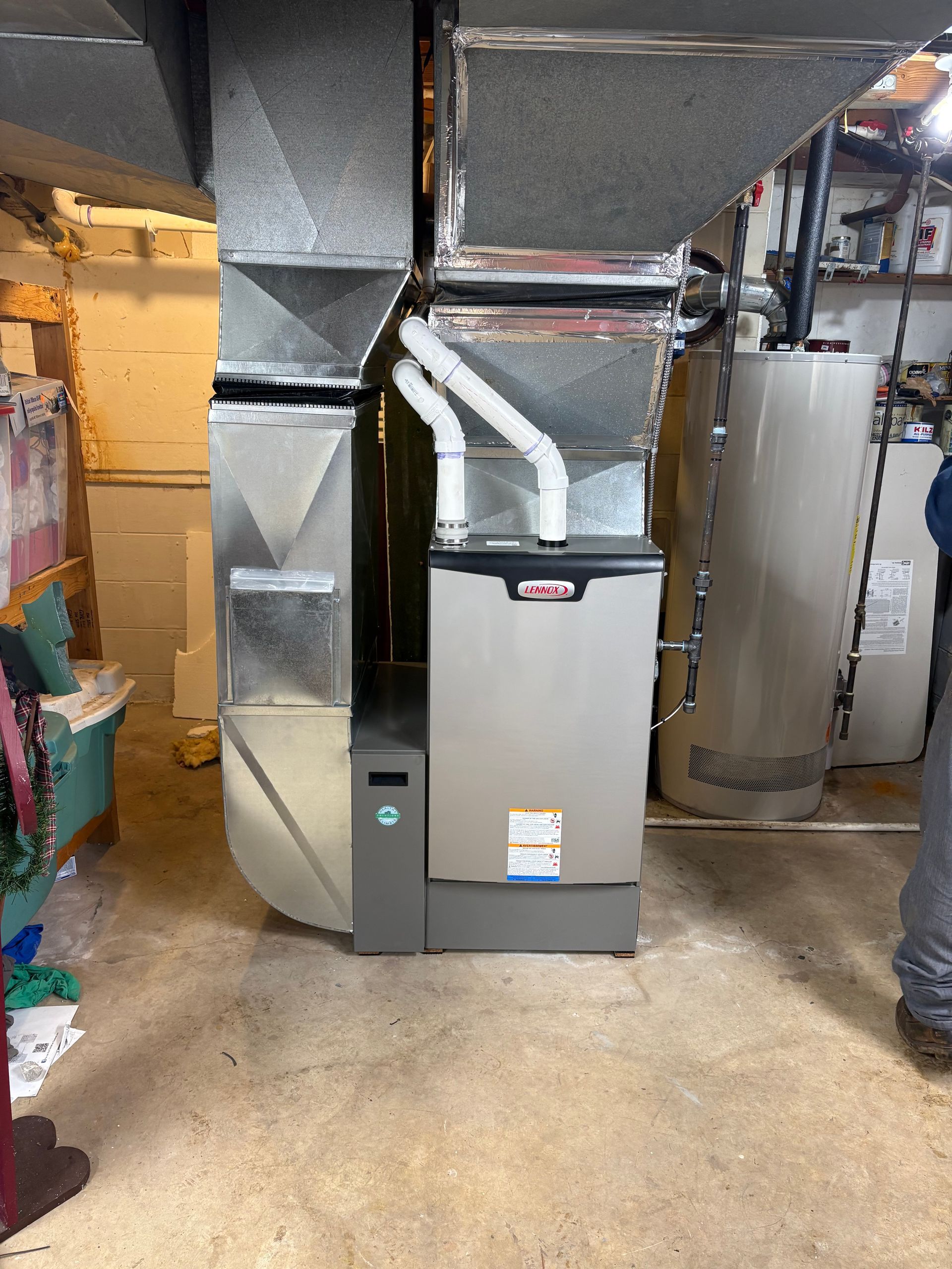 Man adjusts controls on a white water heater in a utility room.