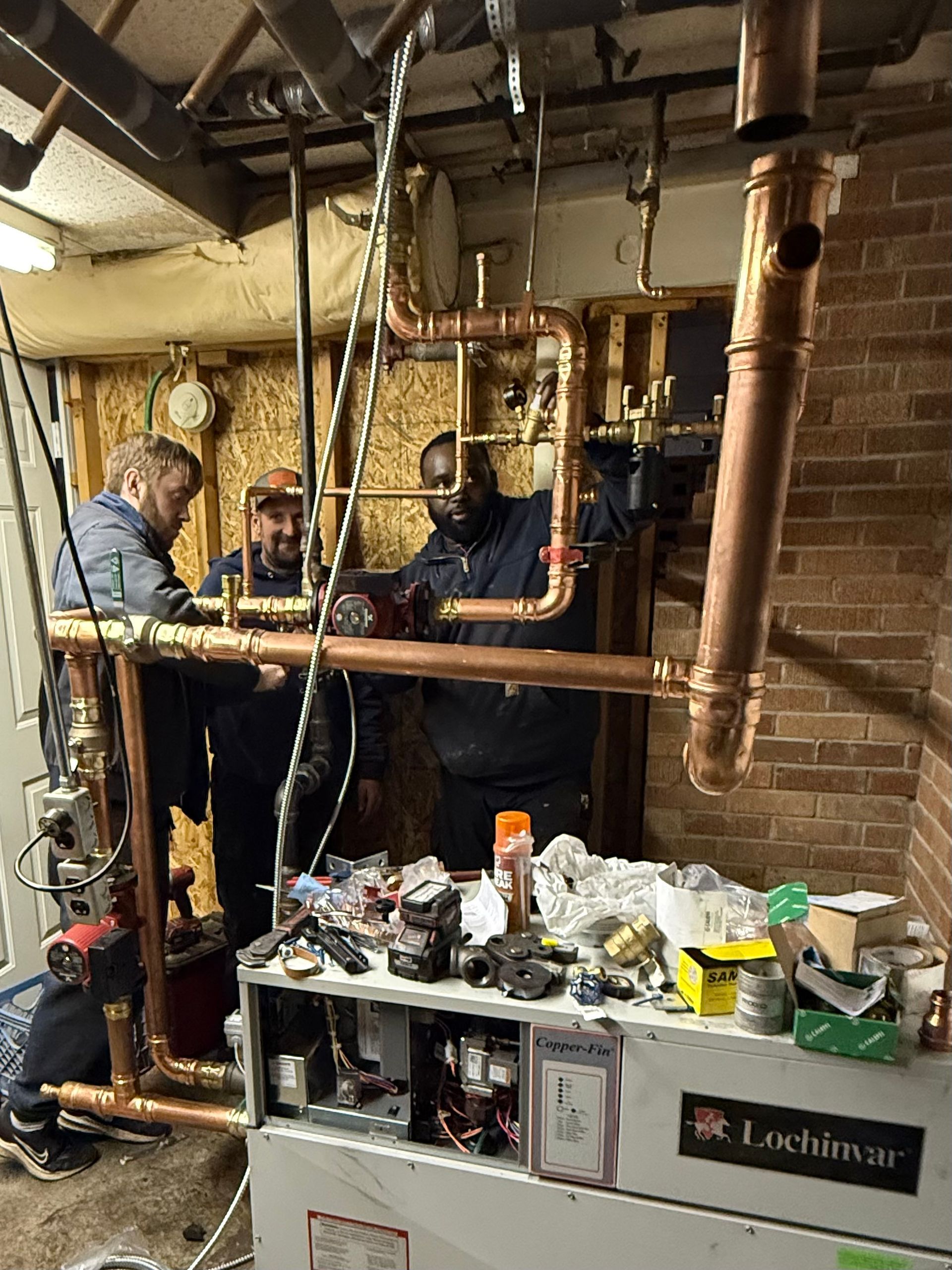 HVAC technician in blue overalls checks gauges on an air conditioning unit.