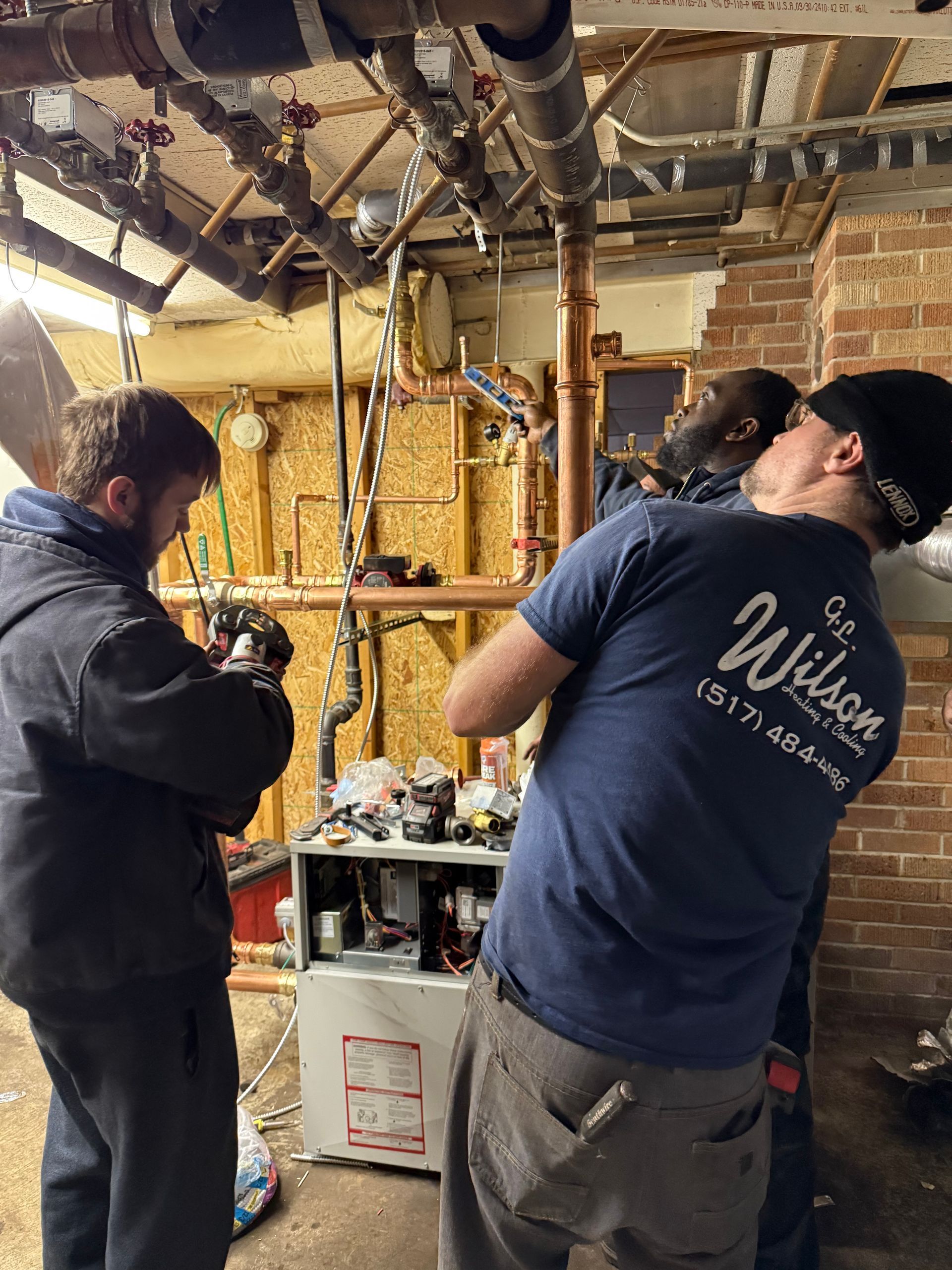 Person using a red-handled screwdriver to loosen a screw on a white vent cover.