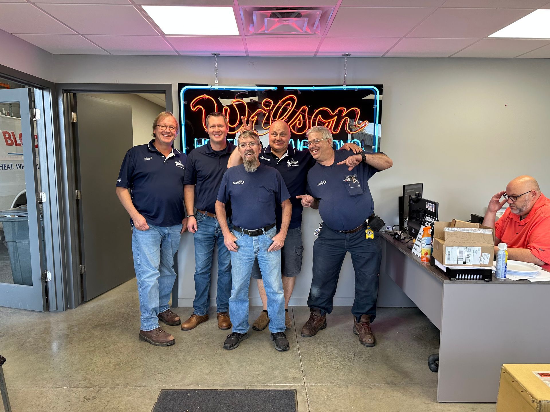 Plumber in red overalls working on copper pipes connected to a heating system.