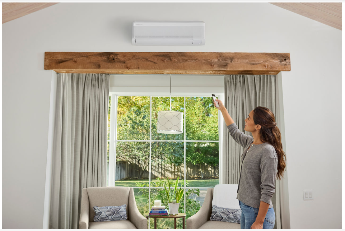 White air conditioning unit mounted on a white wall near white curtains.