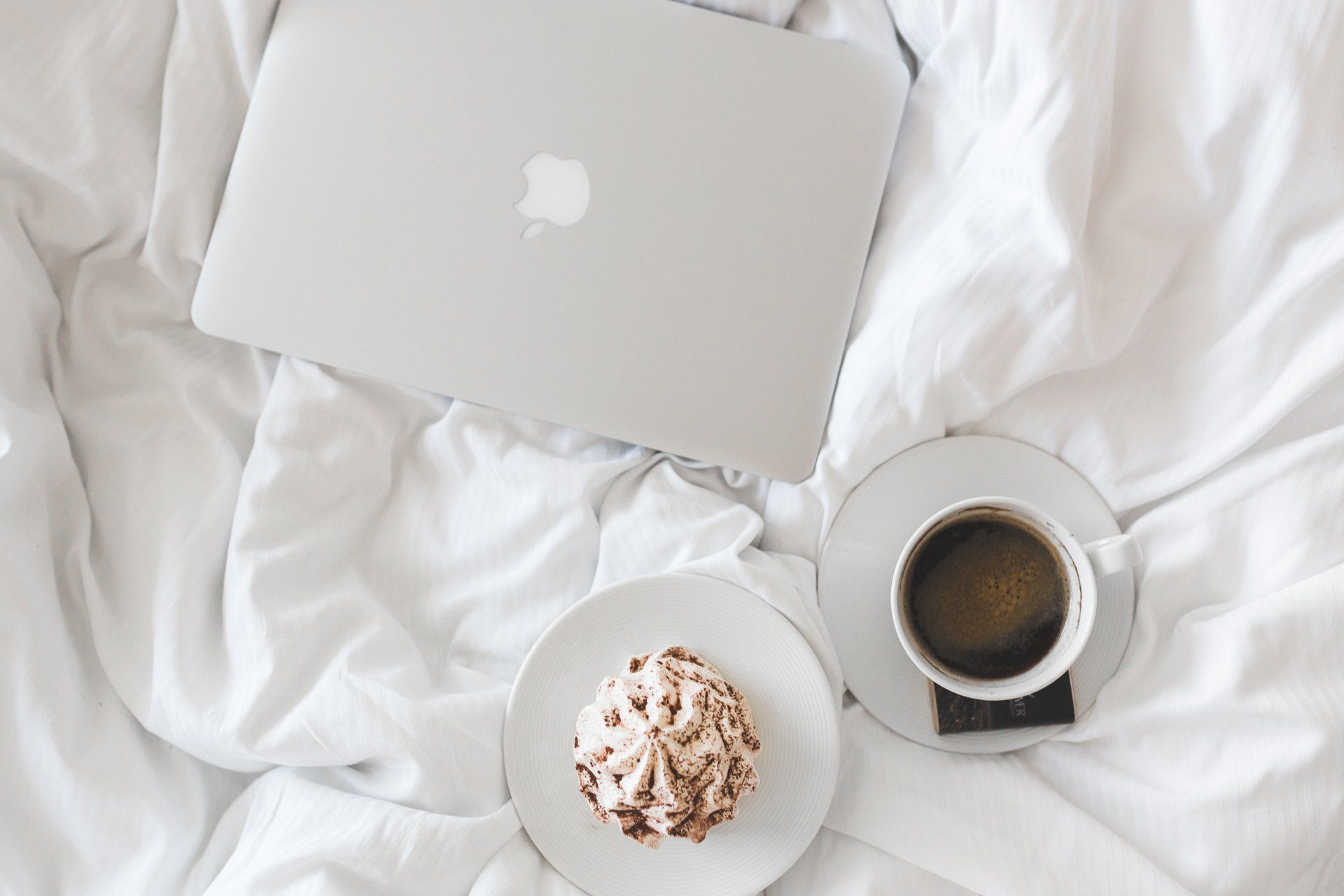 coffee dessert and laptop on bed duvet