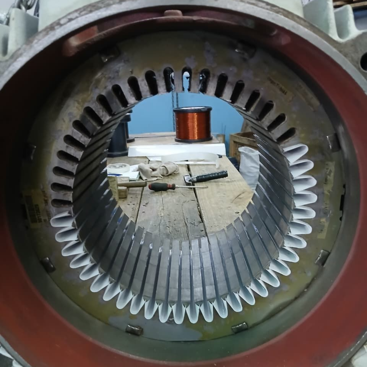 Interior del estator de un motor eléctrico, mostrando ranuras con aislamiento blanco y una bobina de cobre en el fondo.