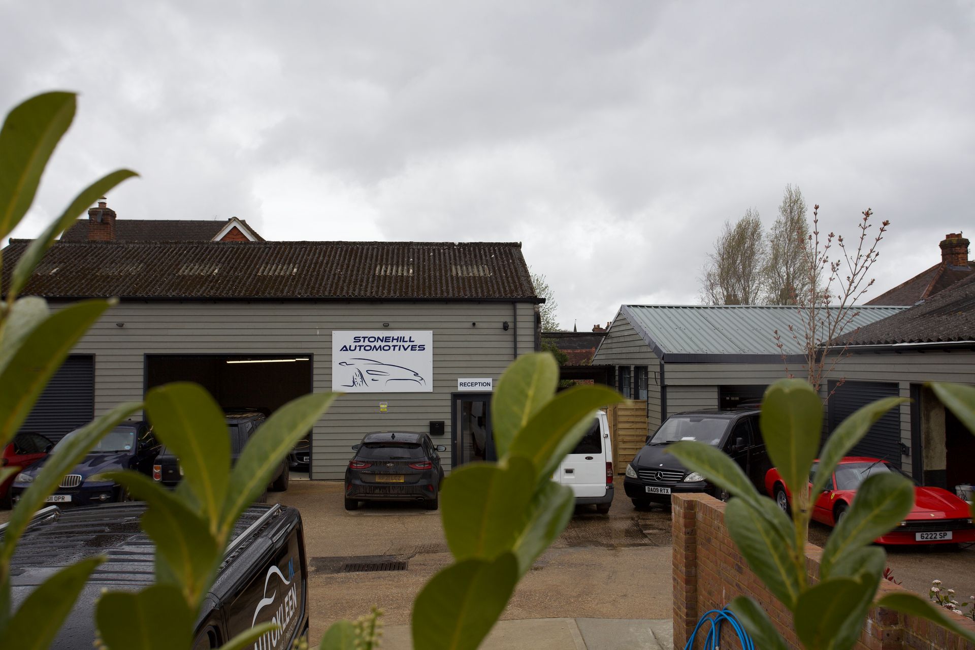 A garage with cars parked in front of it and a sign that says ' automotive ' on it