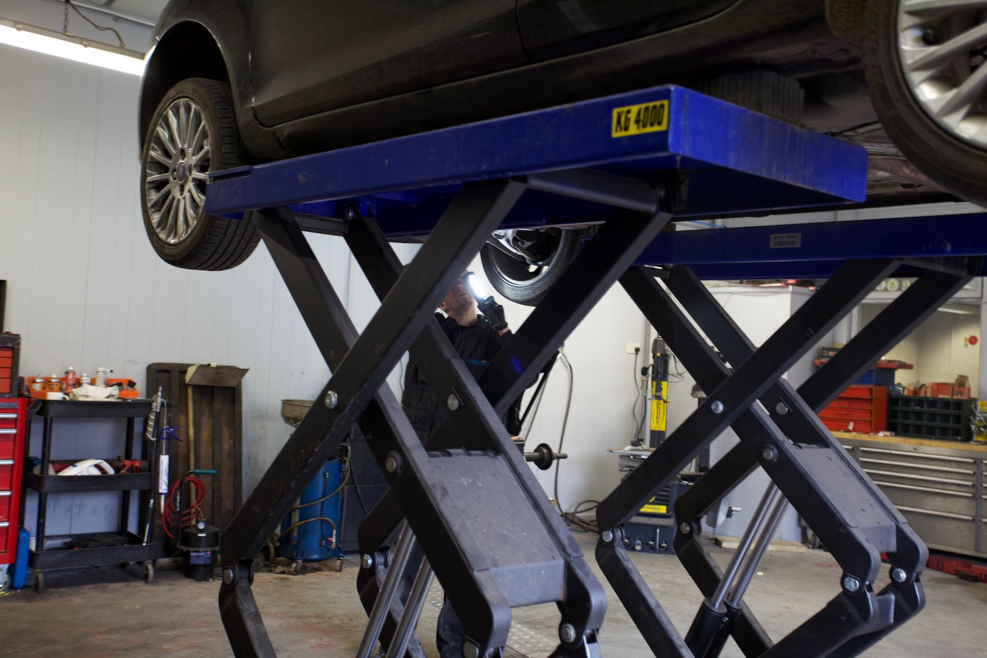 A car is sitting on top of a scissor lift in a garage.