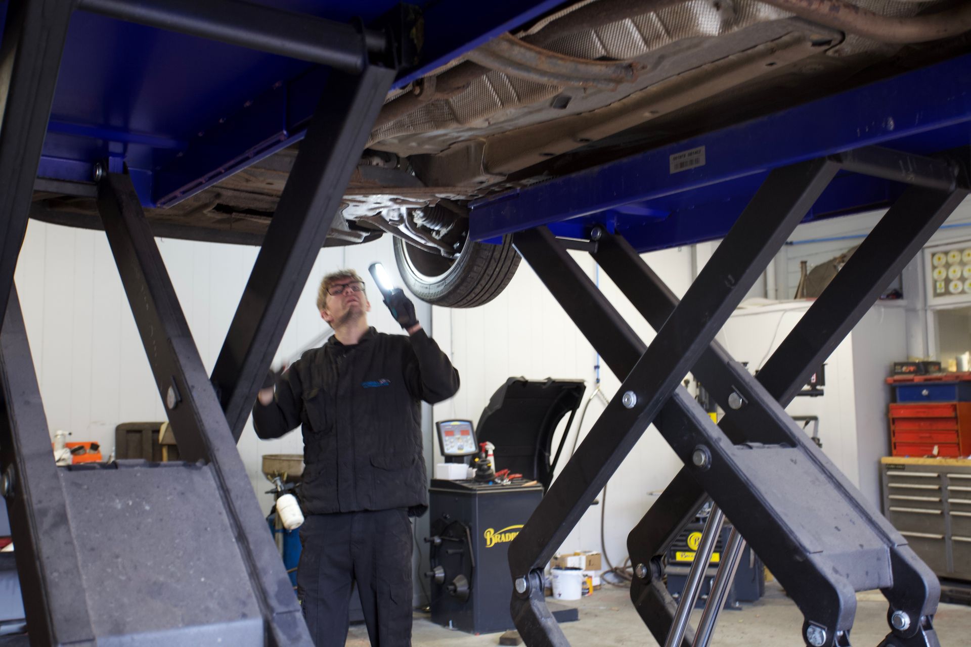 A man is working under a car on a lift