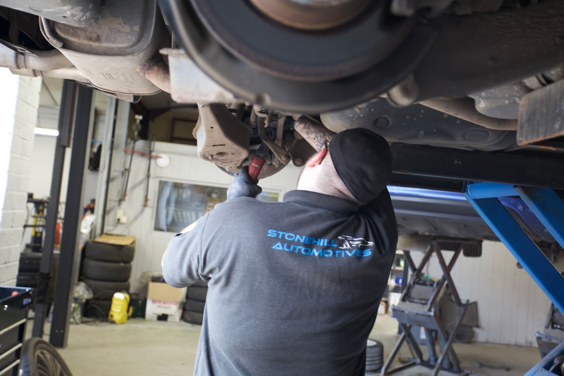 A man is working underneath a car in a garage.