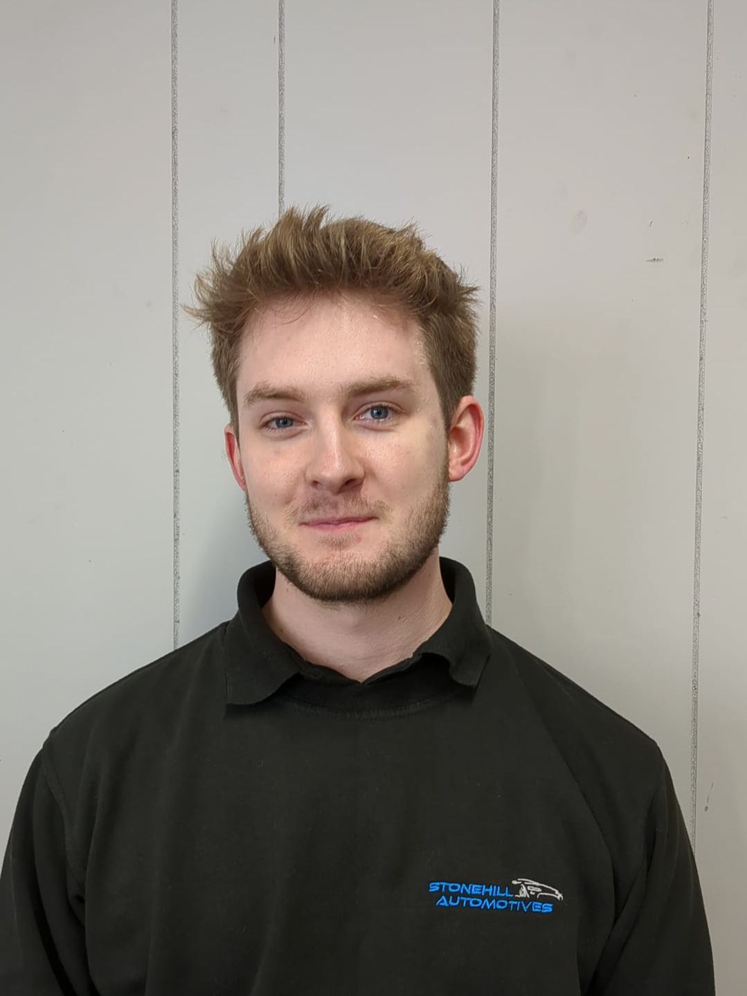 A young man with a beard is wearing a black shirt.