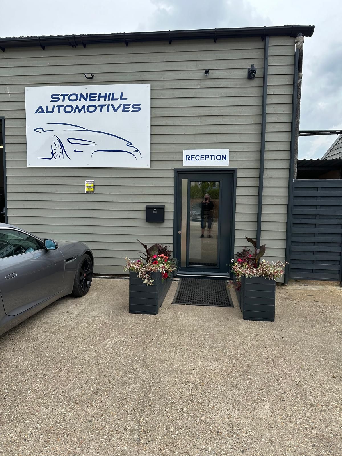 A car is parked in front of a building that says stonehill automotives.