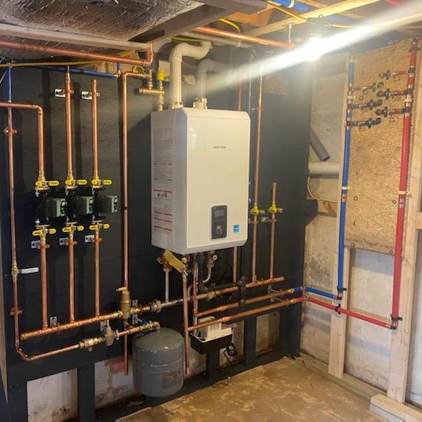 Plumbing system with a water heater, pipes, and valves mounted on black and wood panels in a basement.