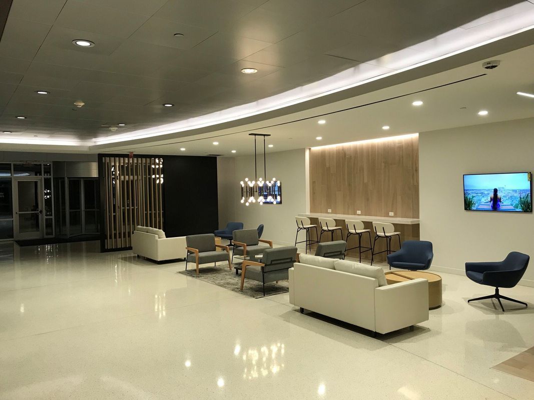 Lobby with white floors, seating areas, a bar, and a television on the wall.
