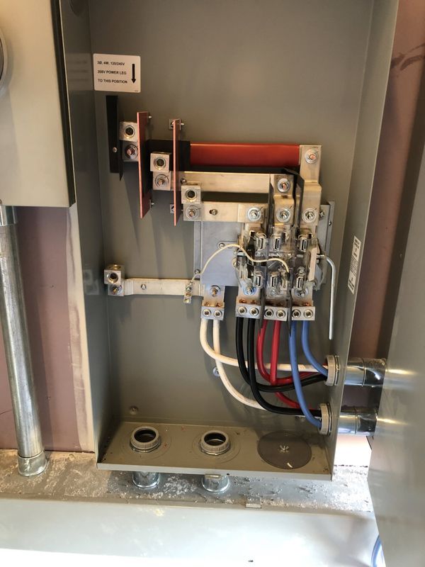 Open electrical panel with wires and switches, gray metal box, indoor setting.